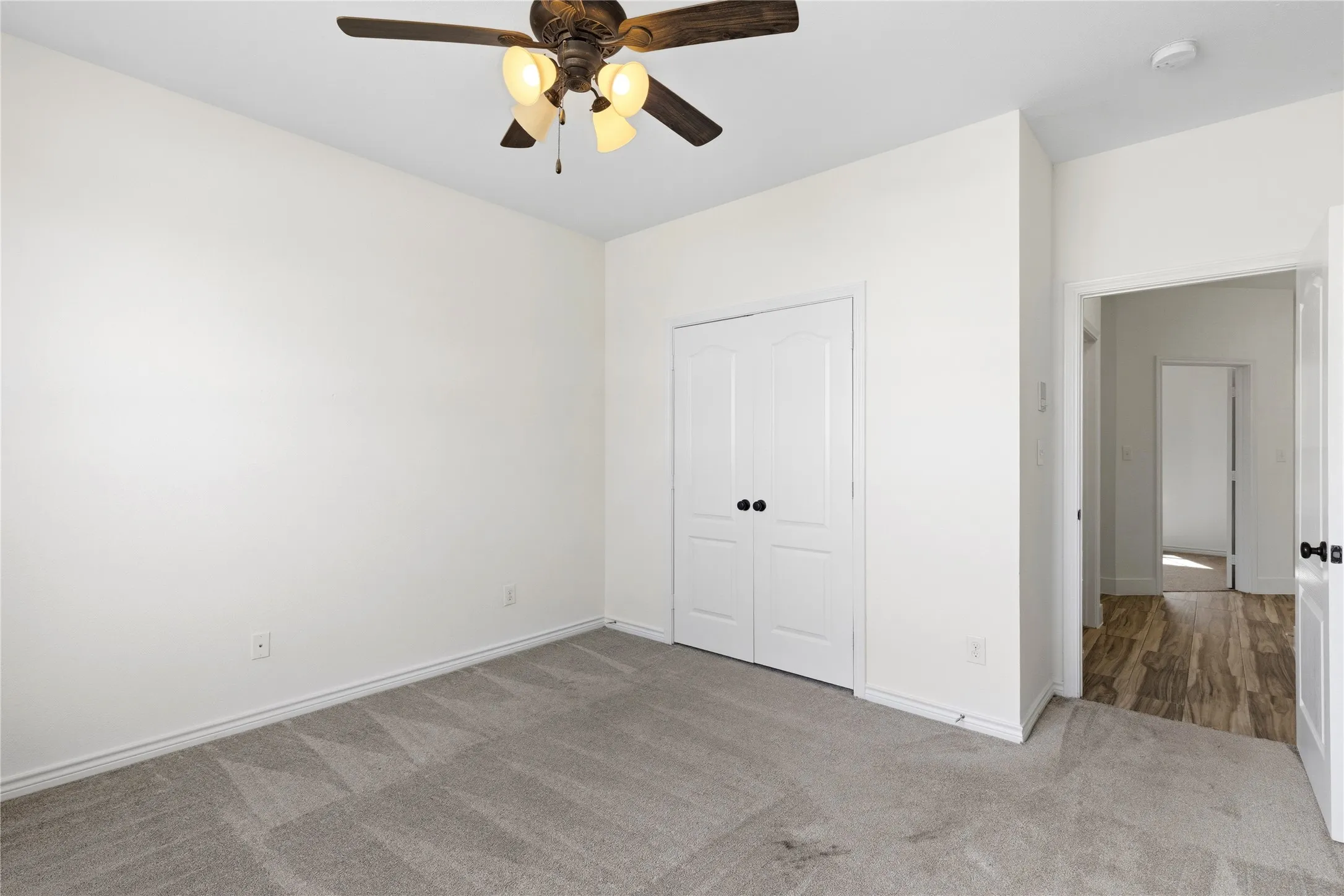 Room featuring light gray carpeting, a ceiling fan with integrated lighting, and white walls