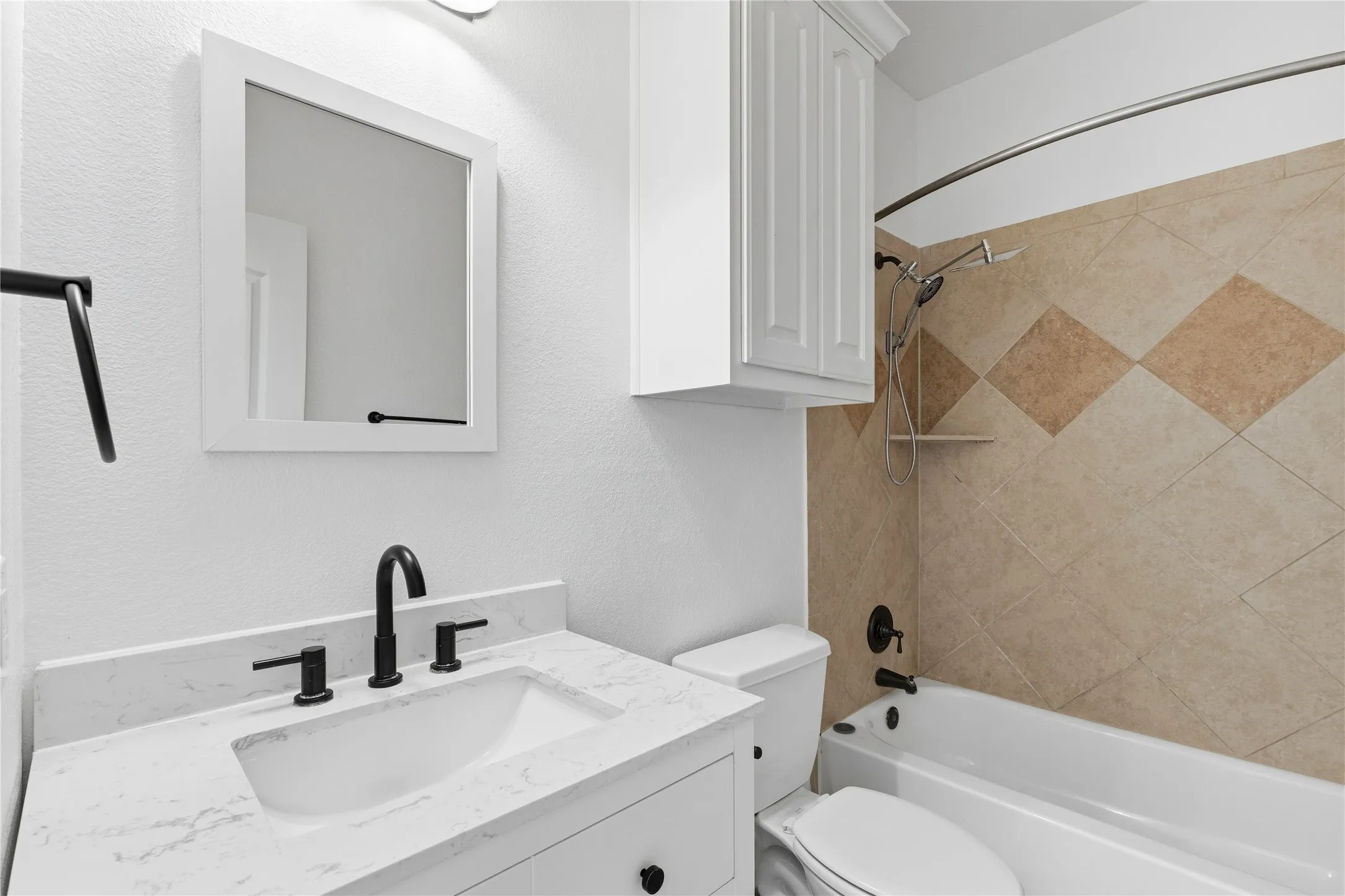 Bathroom featuring a white vanity with an integrated sink and matte black fixtures