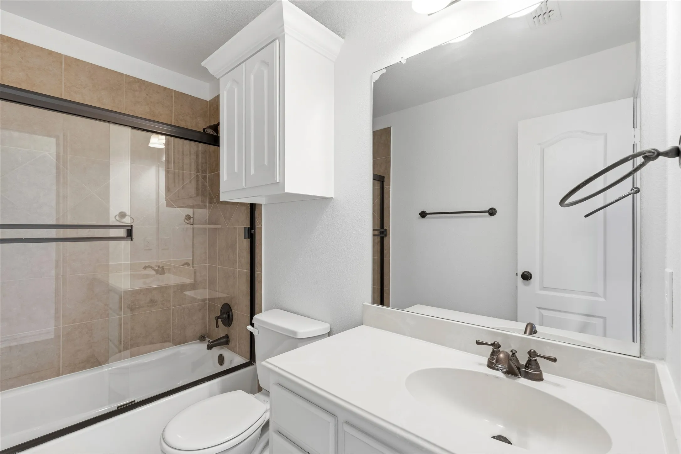 Full bathroom featuring a white vanity with an undermount sink and oil-rubbed bronze fixtures, a framed mirror, and a white toilet