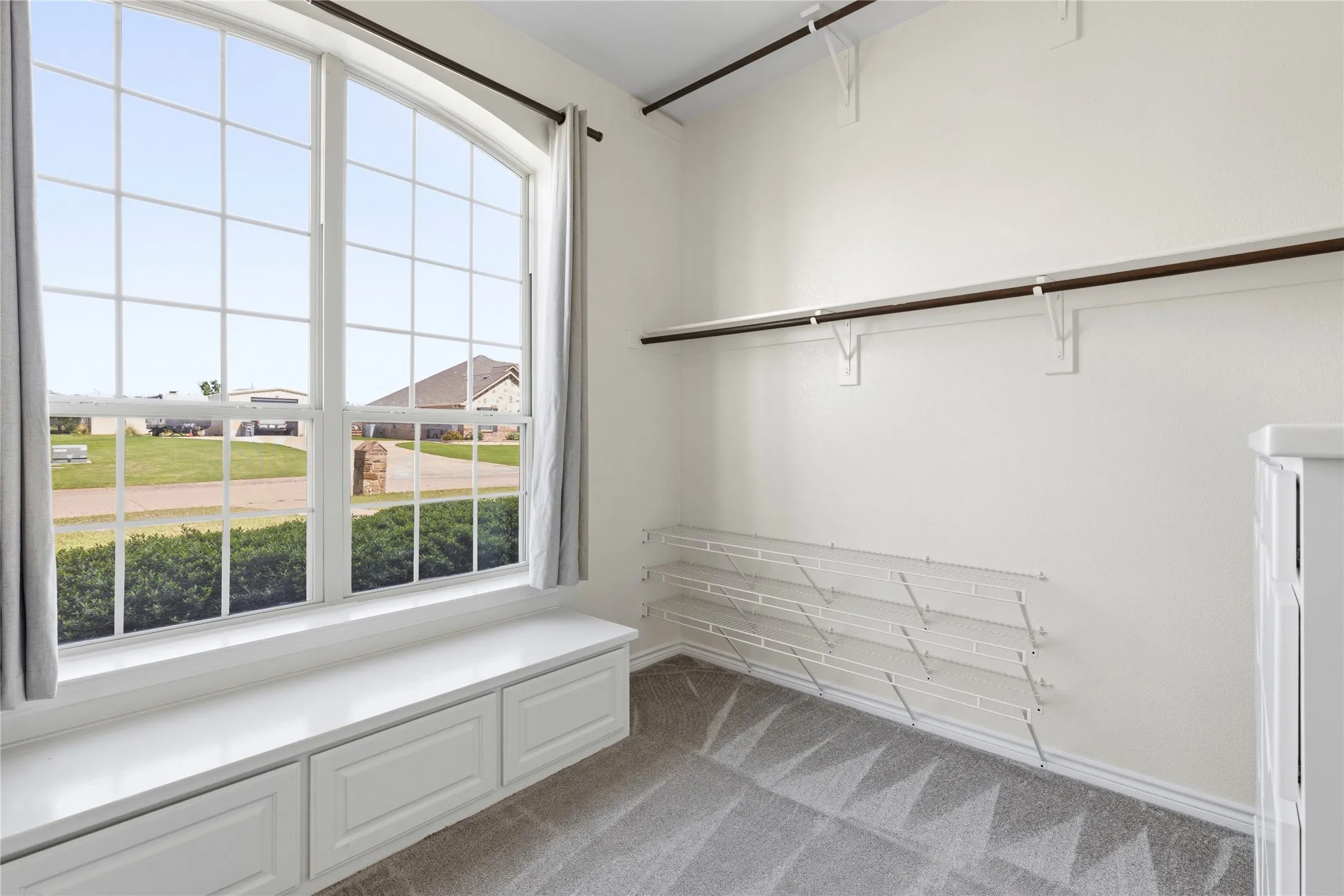 Arched window with grid pattern and built-in window seat featuring storage drawers