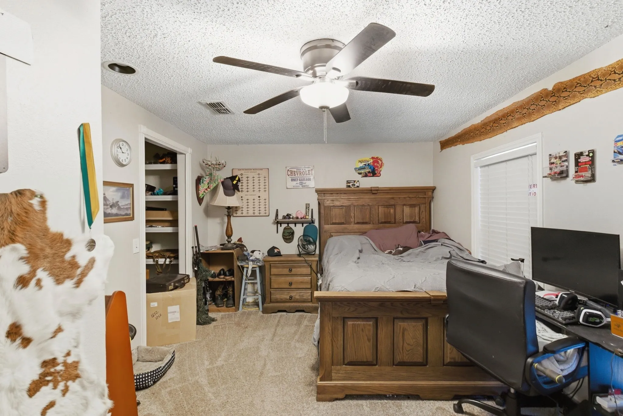 Carpeted room featuring a ceiling fan with integrated lighting, a window with blinds, and a built-in closet with shelving