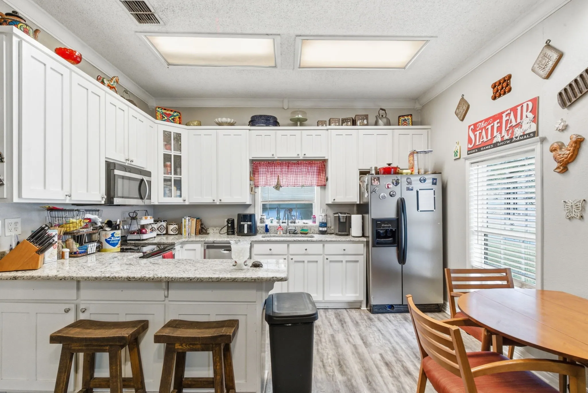 Kitchen featuring white shaker-style cabinetry, granite countertops, and wood-finish flooring