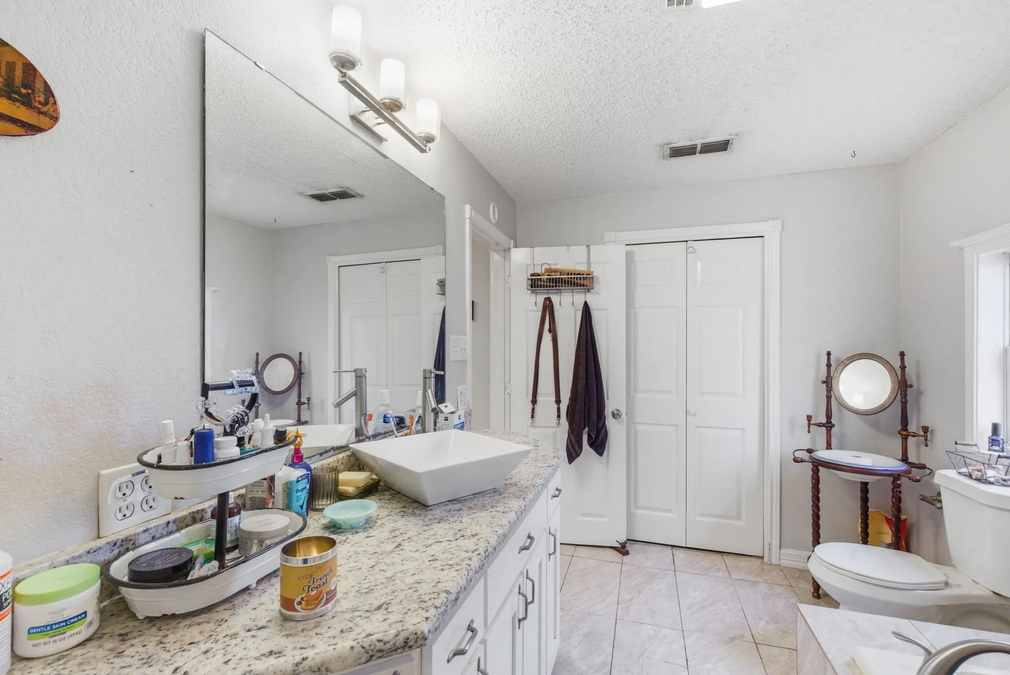 Bathroom vanity featuring a vessel sink, single-handle faucet, and granite-style countertop