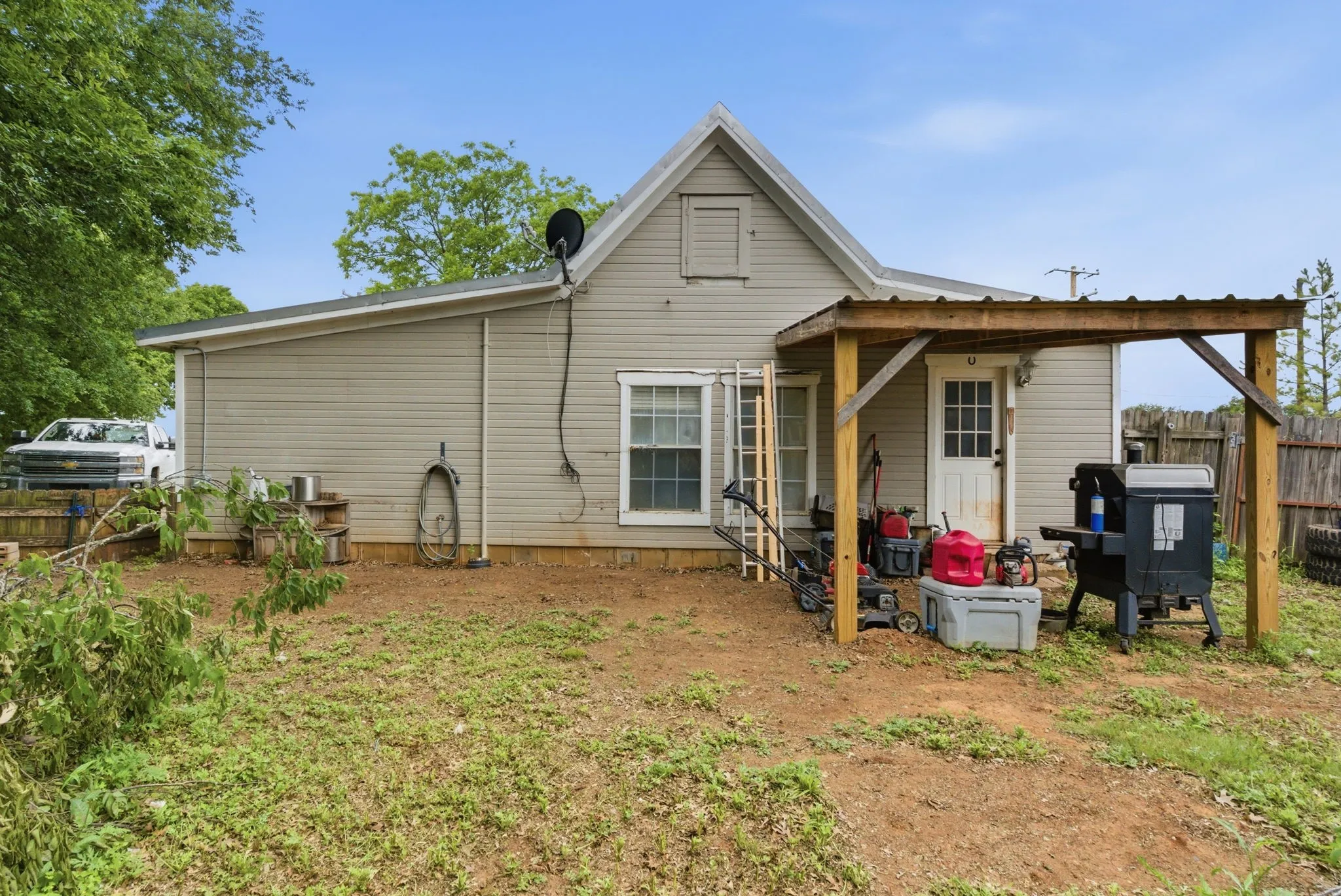 Rear exterior with light-colored siding, a covered patio area, and a white entry door