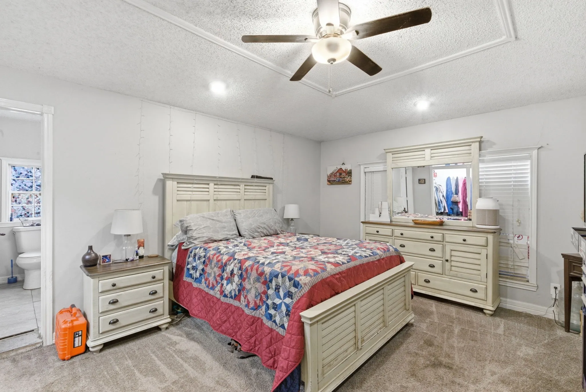 Carpeted room featuring a ceiling fan, recessed lighting, and a doorway opening to a tiled bathroom with a toilet and window