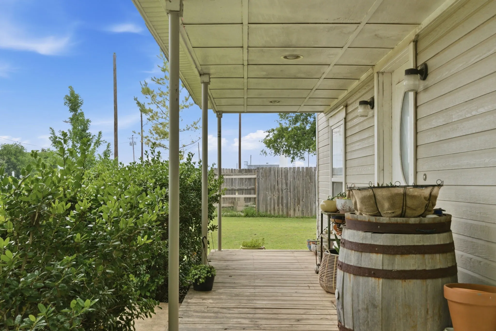 Covered wood-finish porch featuring vertical support columns, horizontal siding, and exterior lighting fixtures