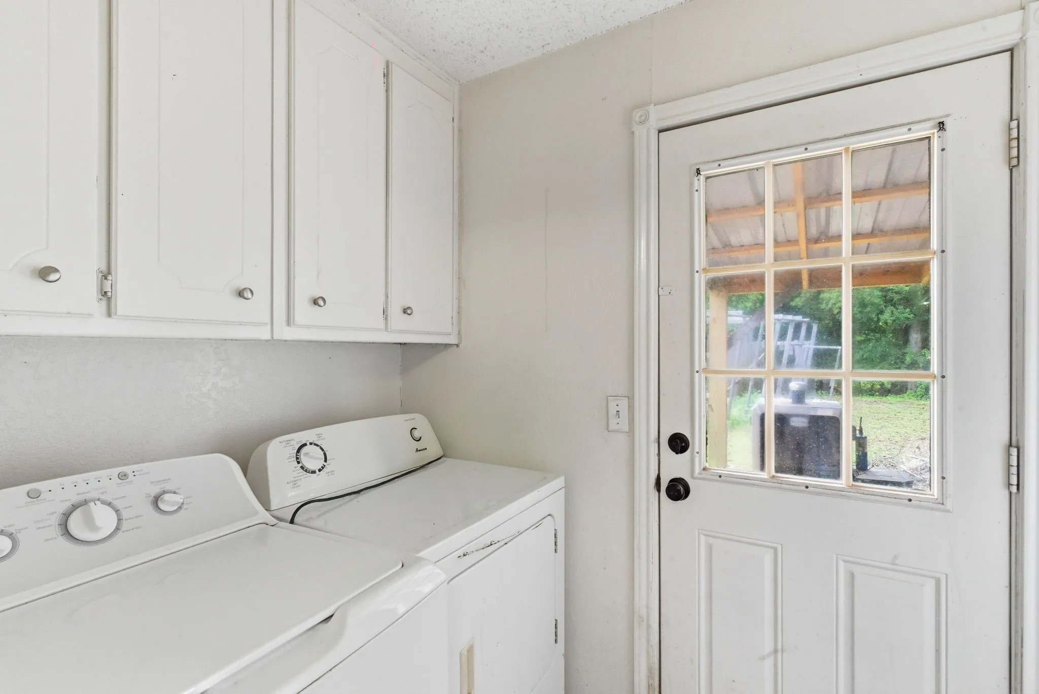 Utility room featuring white cabinetry, a glass-paned exterior door, and light-toned walls