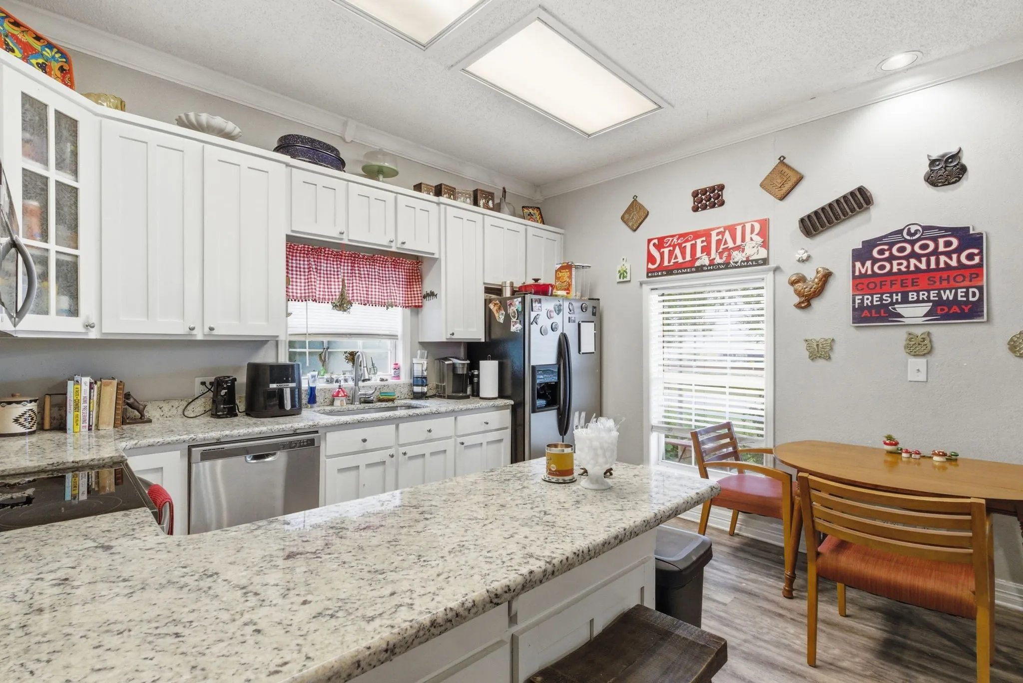 Kitchen featuring white cabinetry, speckled countertops, stainless steel appliances, and wood-finish flooring