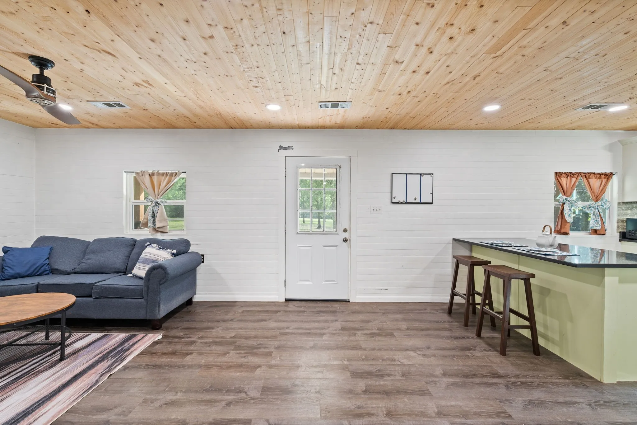 Open-concept living area featuring a light wood-finish plank ceiling, recessed lighting, and wood-finish flooring