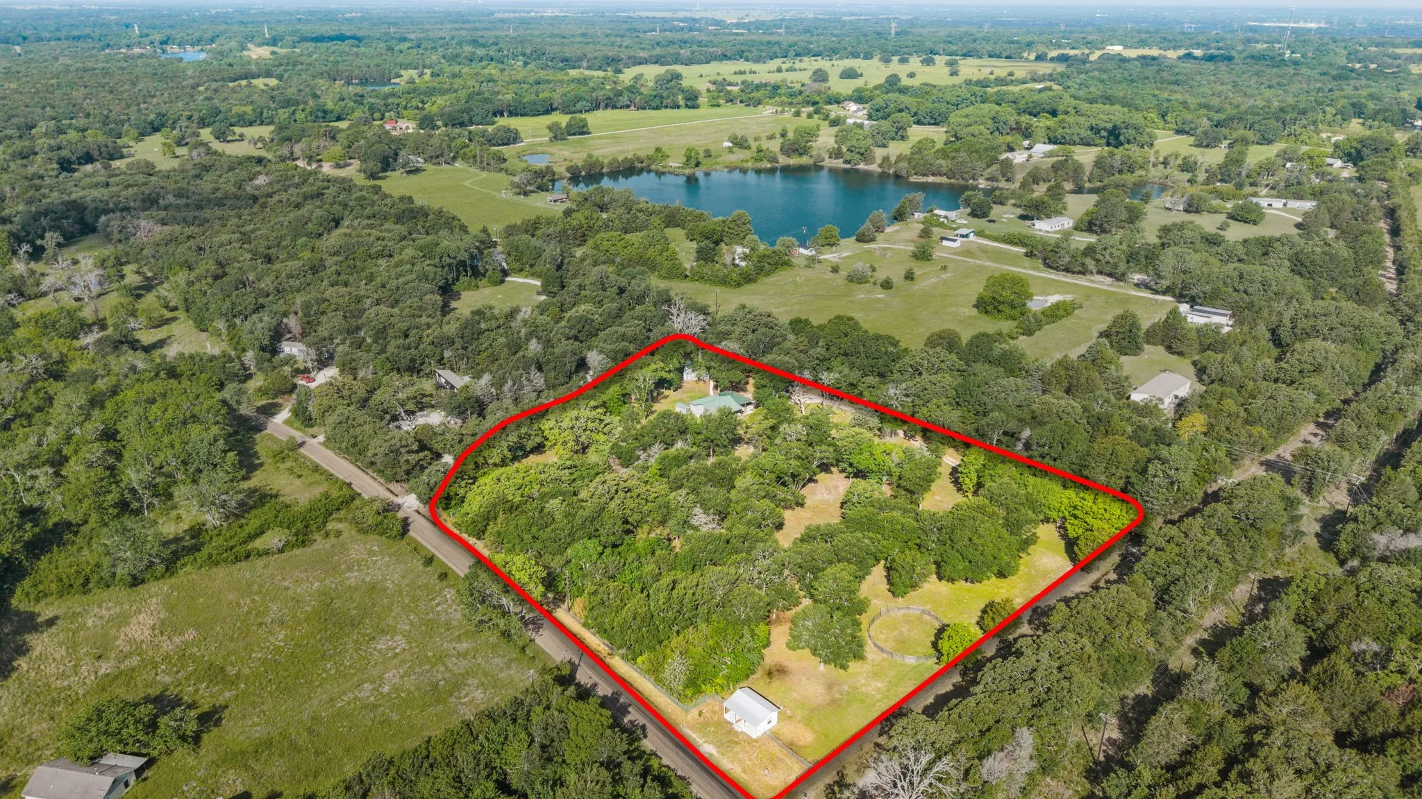 Expansive wooded property featuring a cleared area, a small structure, and a perimeter outlined in red
