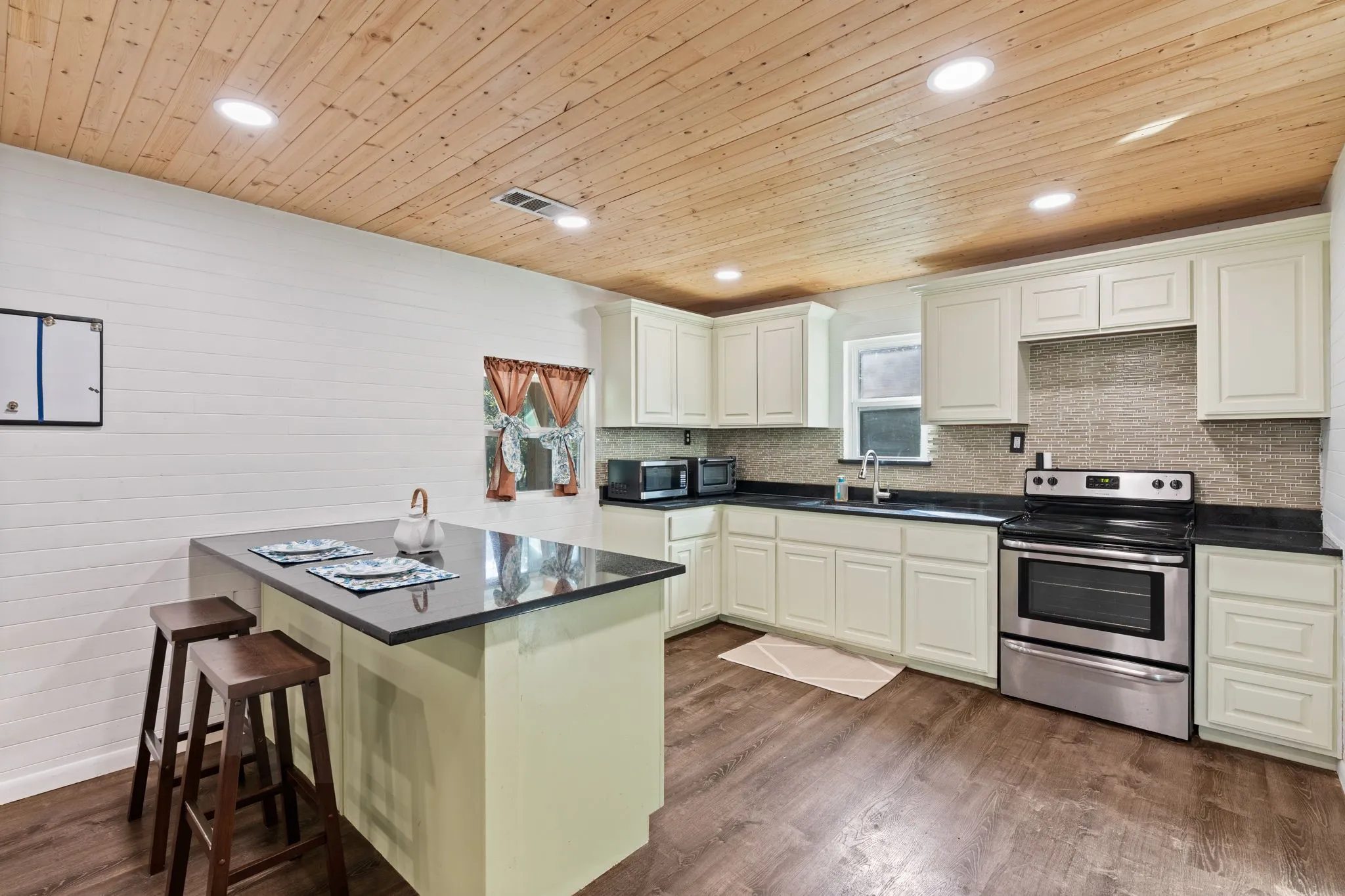 Kitchen featuring light-colored cabinetry, dark countertops, and a full stainless steel range