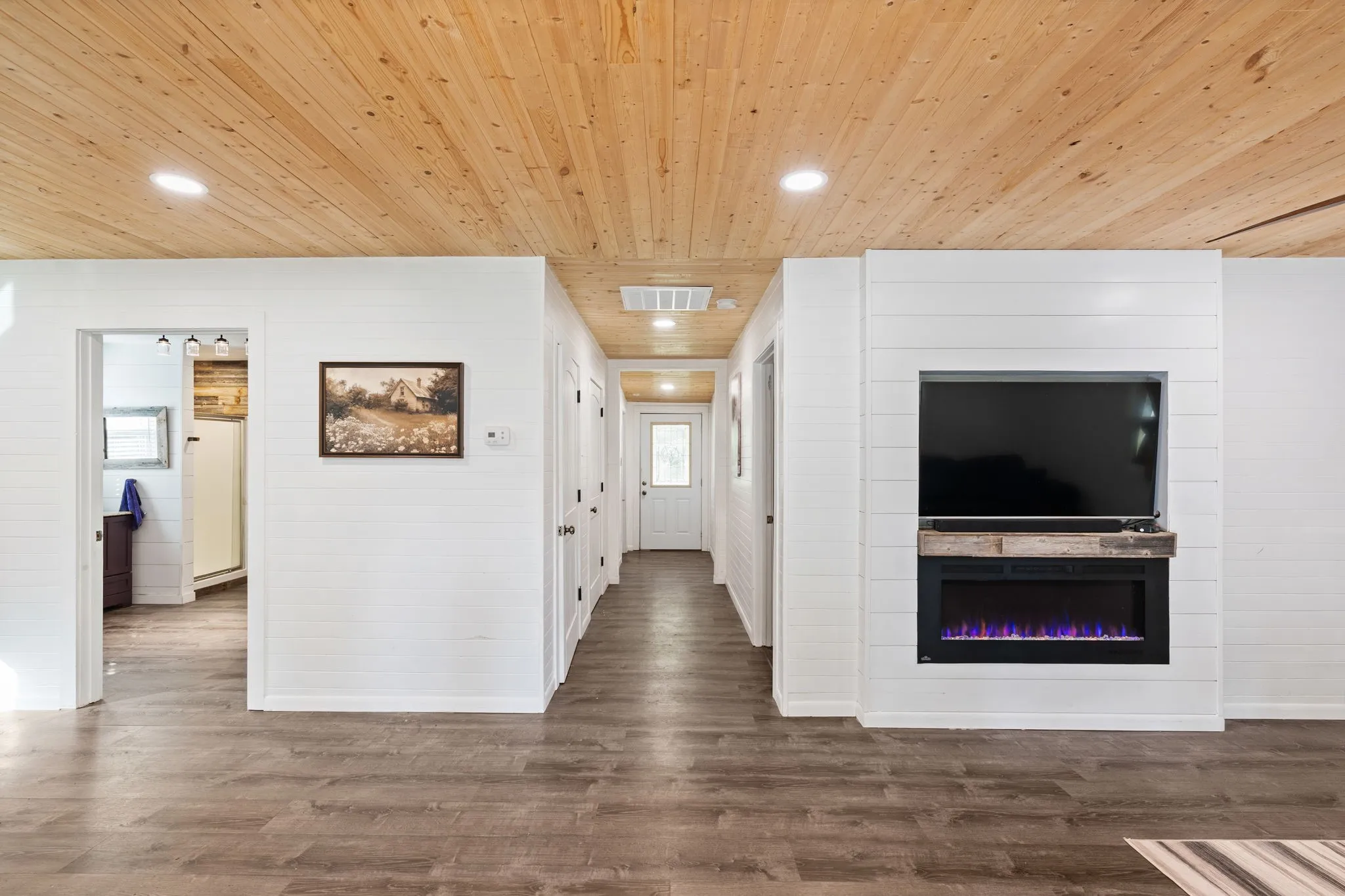 Shiplap accent wall featuring a built-in electric fireplace with a wood-finish mantel and recessed space for a television
