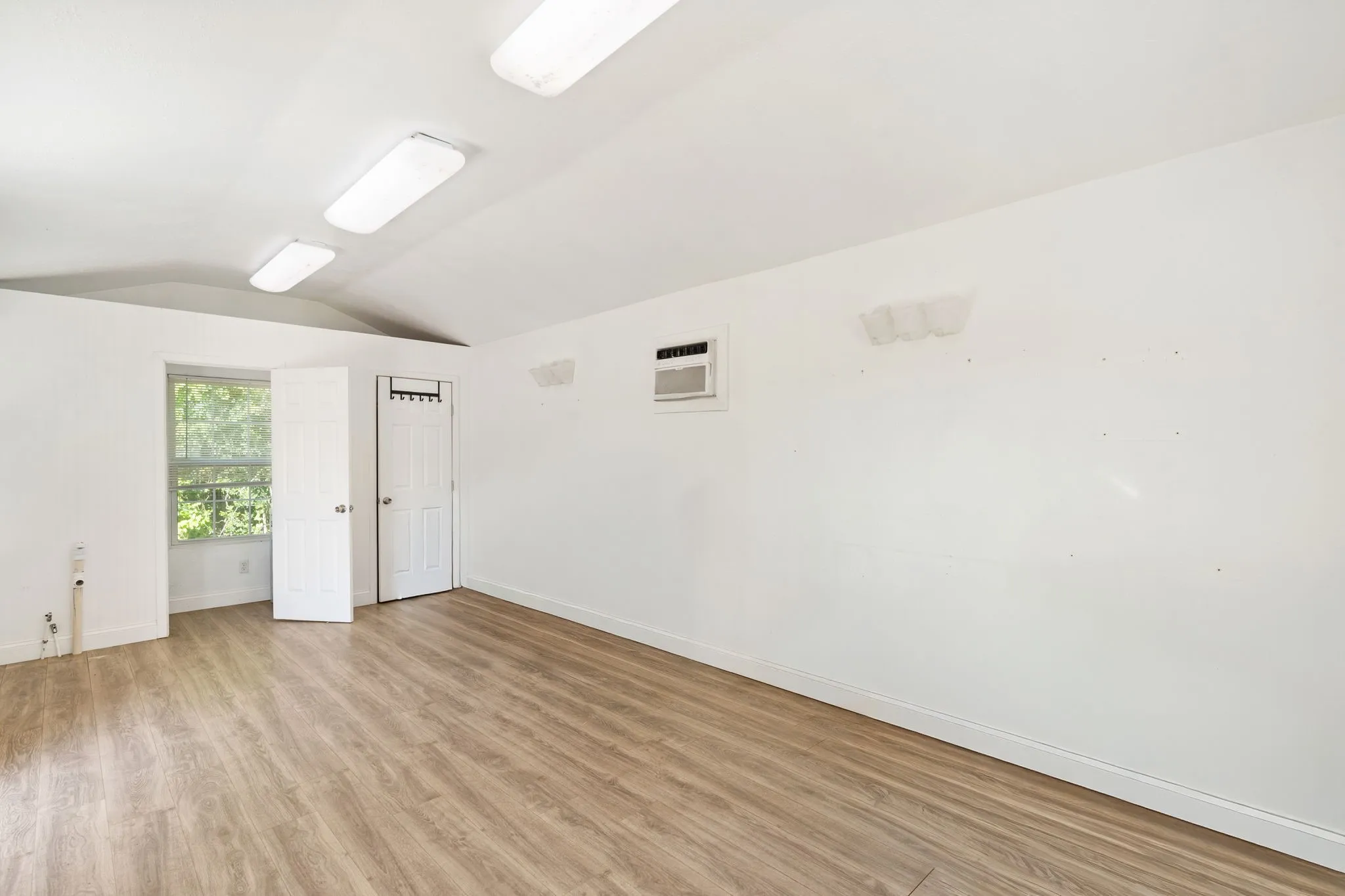 Secondary featuring wood-finish flooring, white walls, and a vaulted ceiling