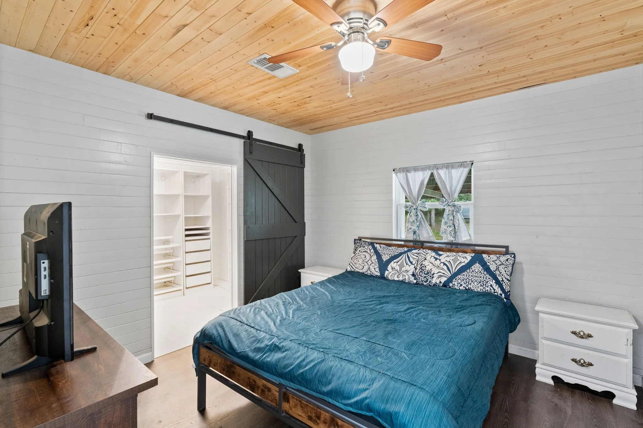 Bedroom featuring a wood-panel ceiling, white shiplap walls, and dark wood-finish flooring