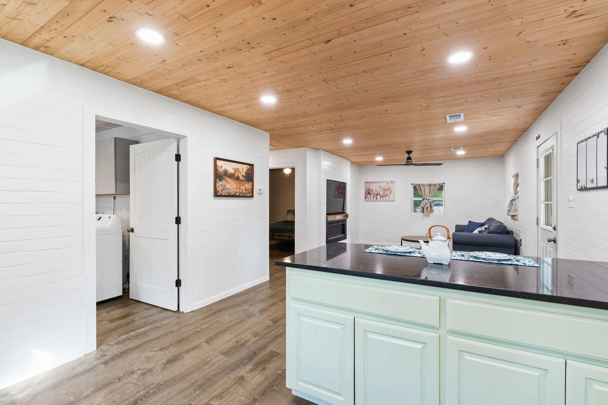Open concept living area featuring wood-finish flooring and a natural wood plank ceiling with recessed lighting