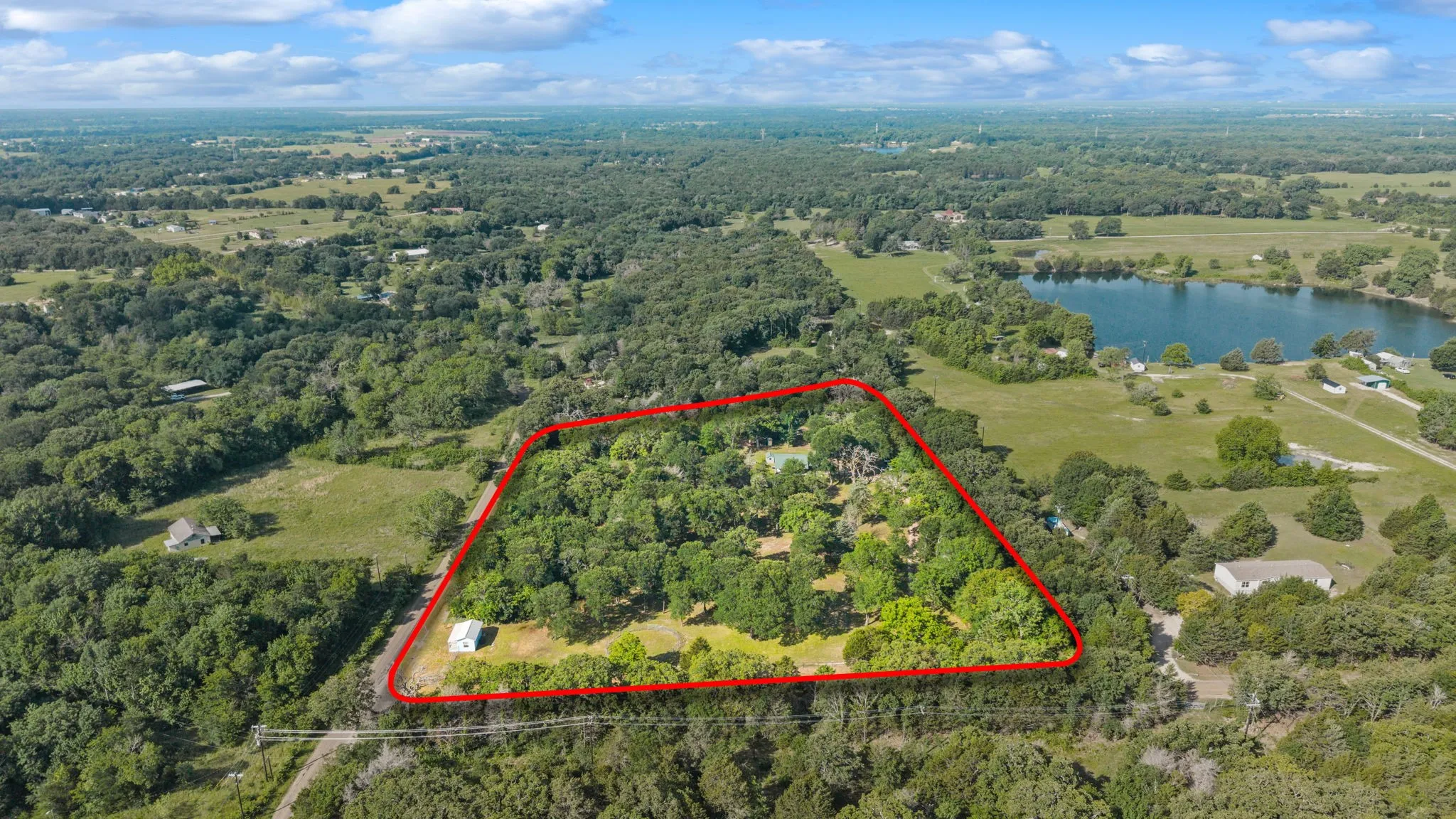 Aerial depiction of a substantial land parcel, outlined in red, featuring extensive tree coverage