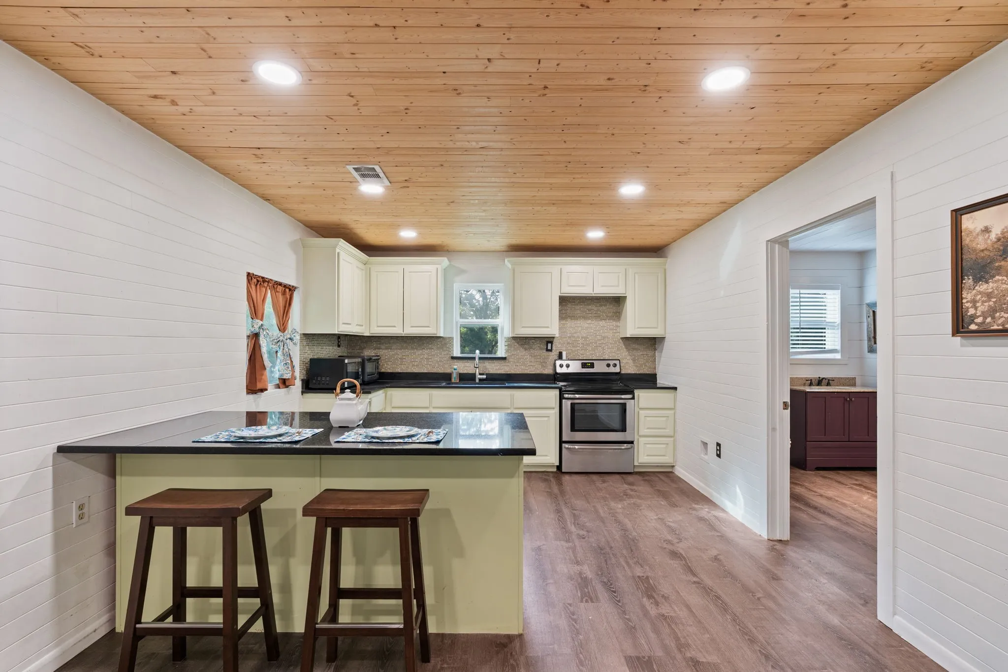 Kitchen featuring a peninsula with dark countertops, cream cabinetry, stainless steel oven, and wood-finish flooring