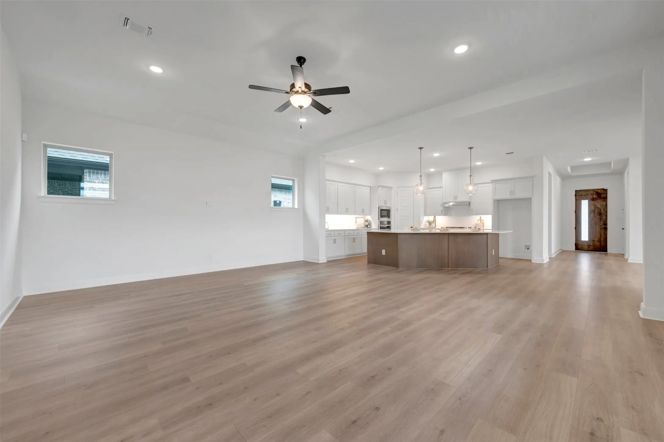 Open-concept living space featuring wood-finish flooring, recessed lighting, and a ceiling fan