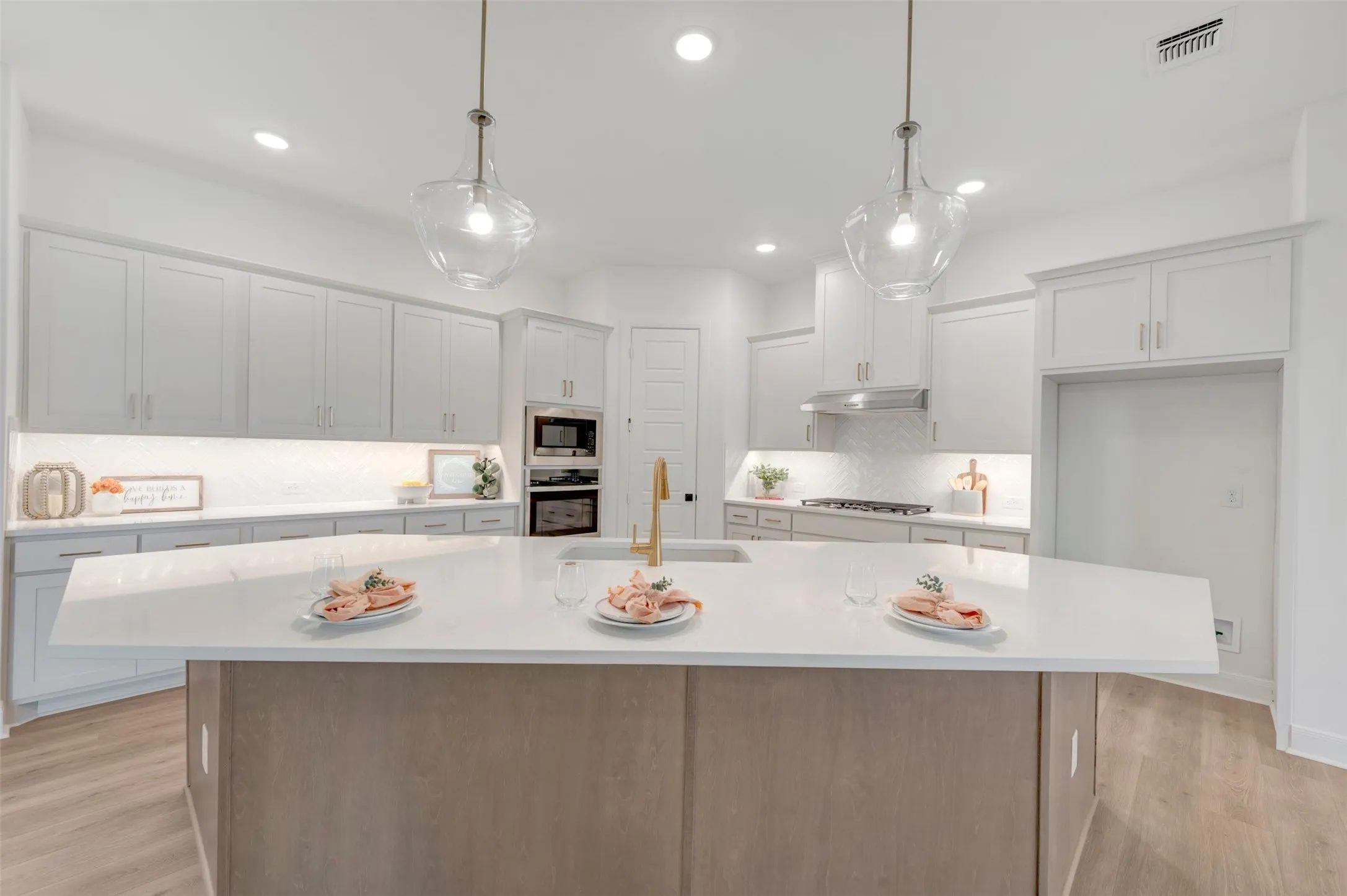Expansive kitchen island with a light-toned countertop, complete with clear pendant lighting