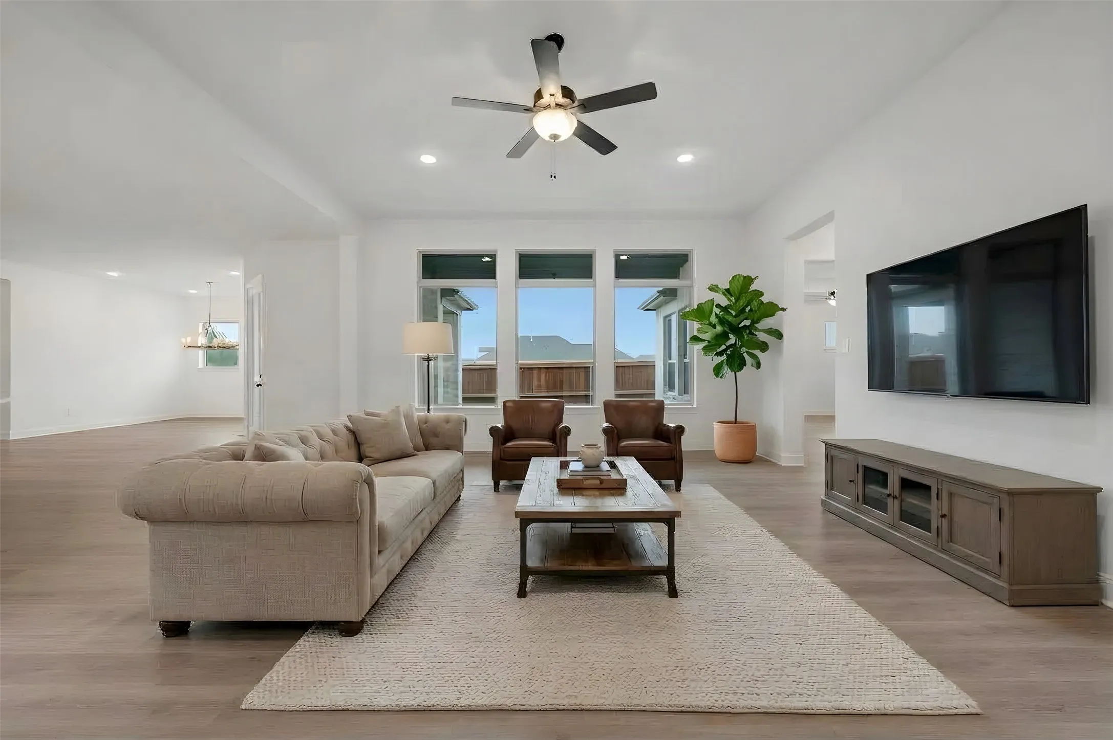 Bright living area with recessed lighting, a ceiling fan, wood-finish flooring, and multiple windows