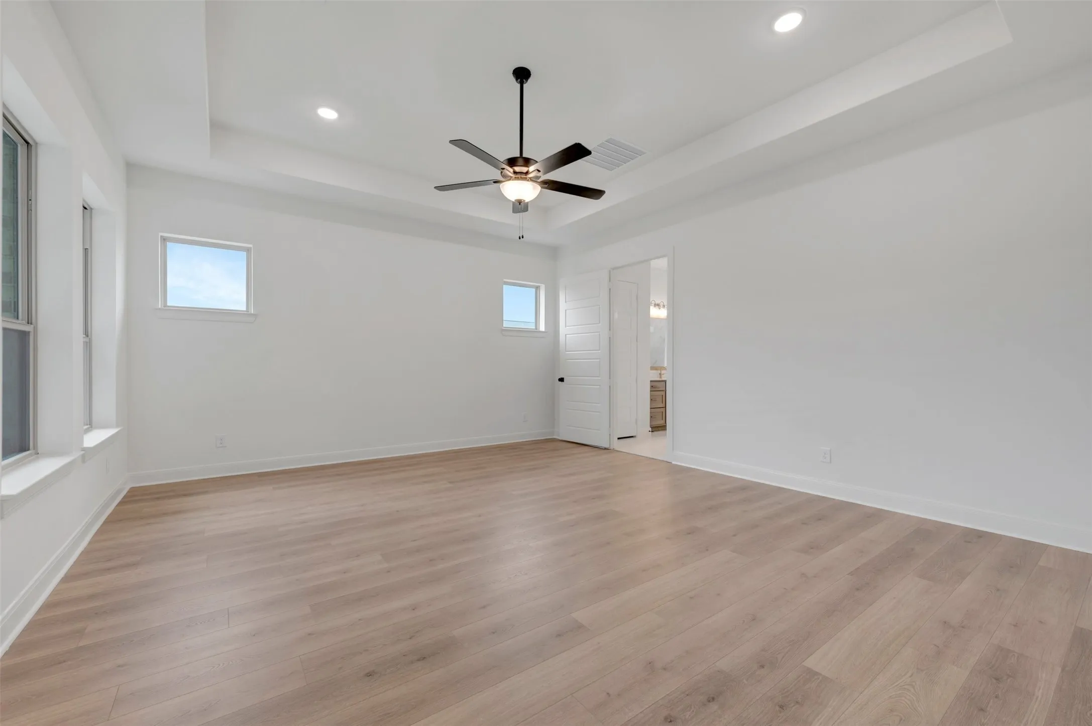 Spacious room with wood-finish flooring, recessed lighting, and a contemporary ceiling fan
