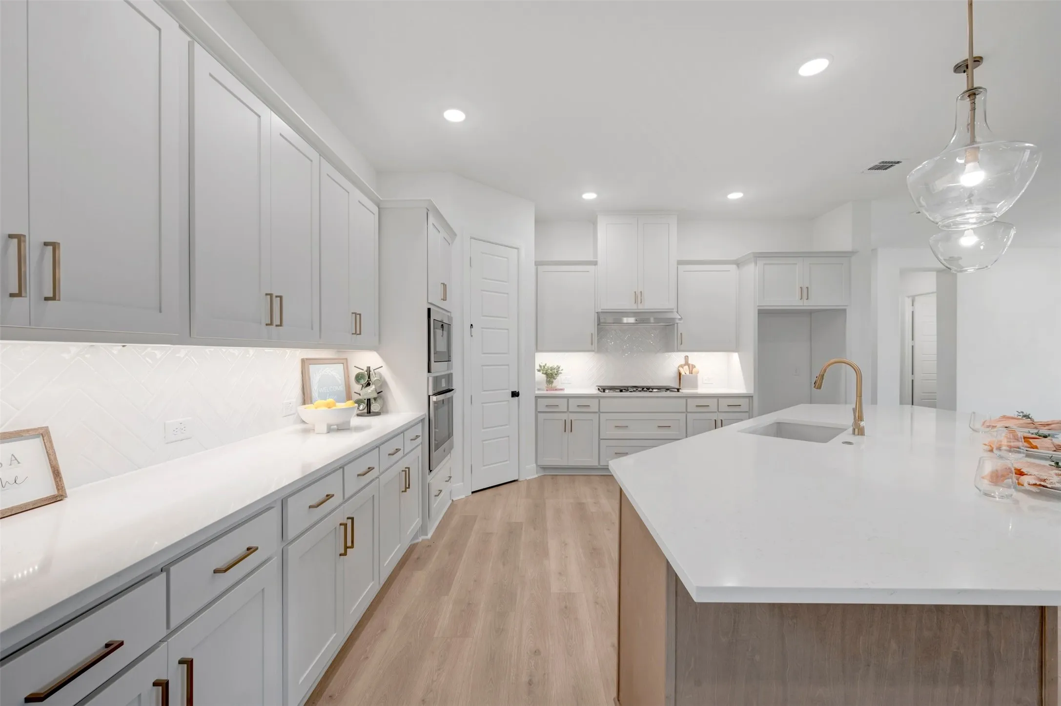 Kitchen featuring an island with an undermount sink, brass-finish faucet, and pendant lighting