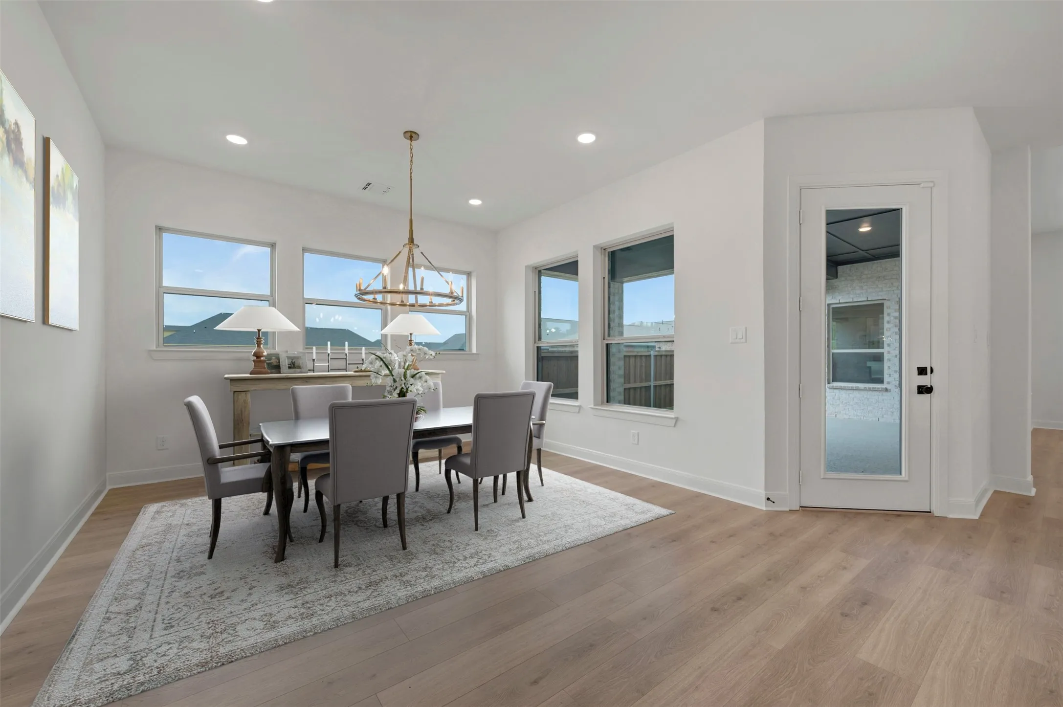 Light wood-finish flooring, recessed lighting, and a modern chandelier