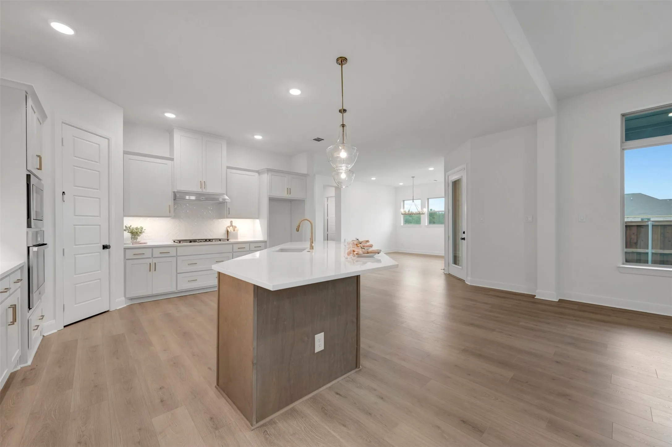Open-concept kitchen with white cabinetry, stainless steel appliances, and a central island with a solid surface countertop