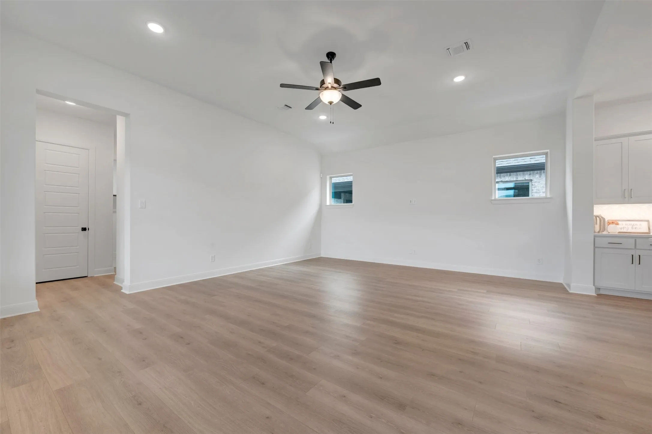 Spacious room featuring wood-finish flooring, recessed lighting, and a ceiling fan