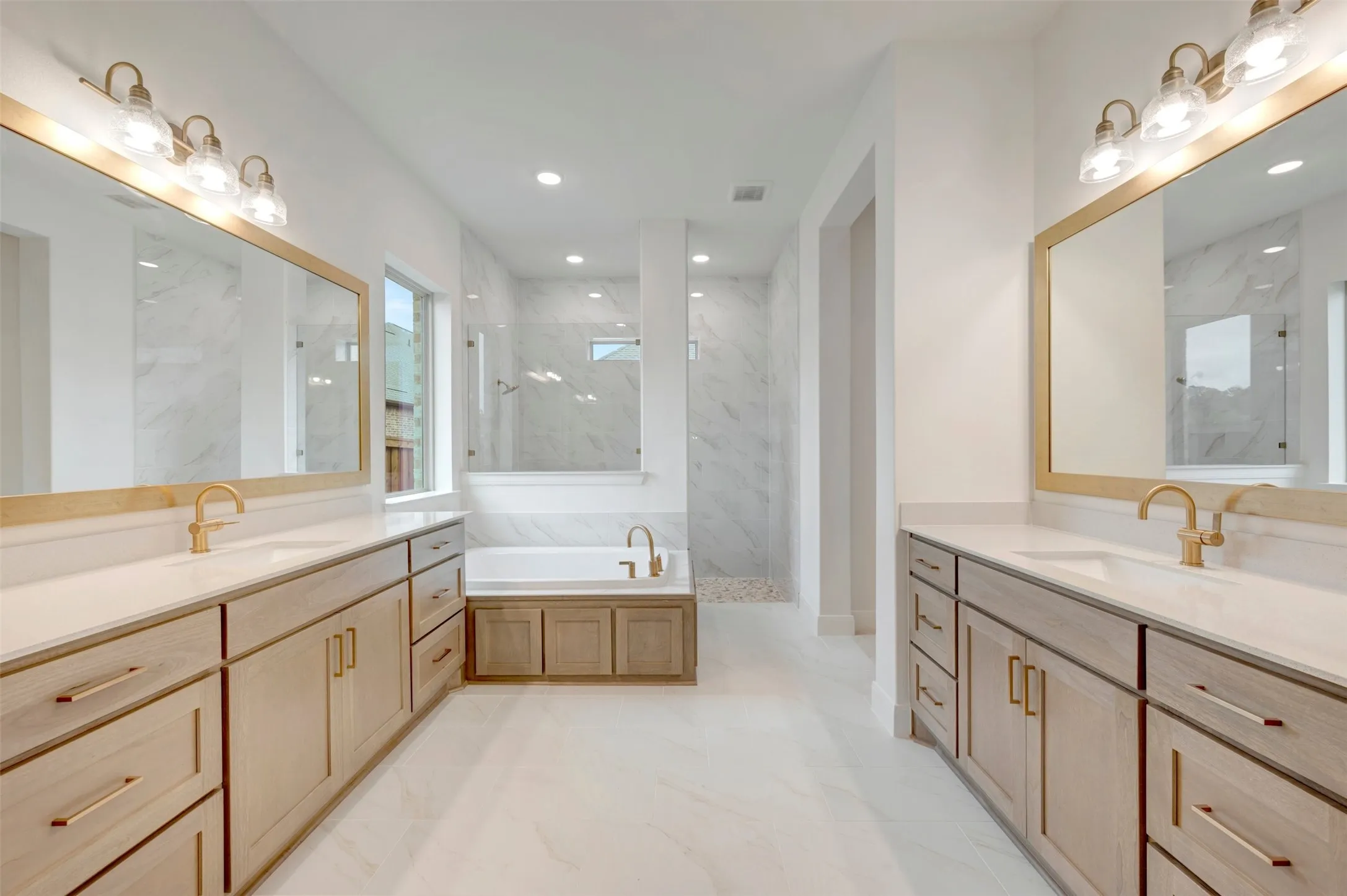 Dual vanities with undermount sinks, gold-finish hardware, and recessed lighting