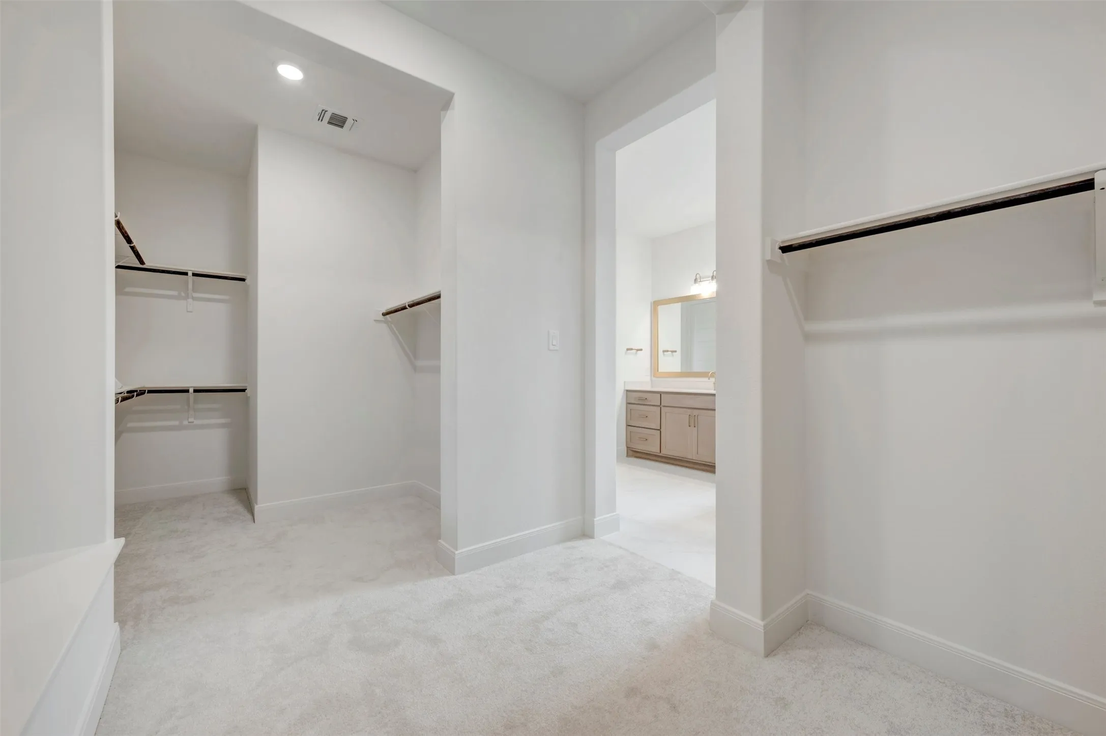Carpeted walk-in closet with built-in shelving, hanging rods, and recessed lighting