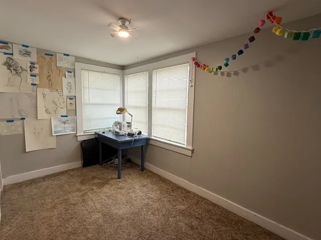 Room featuring corner windows, wall-to-wall carpeting, and a ceiling fan with integrated lighting