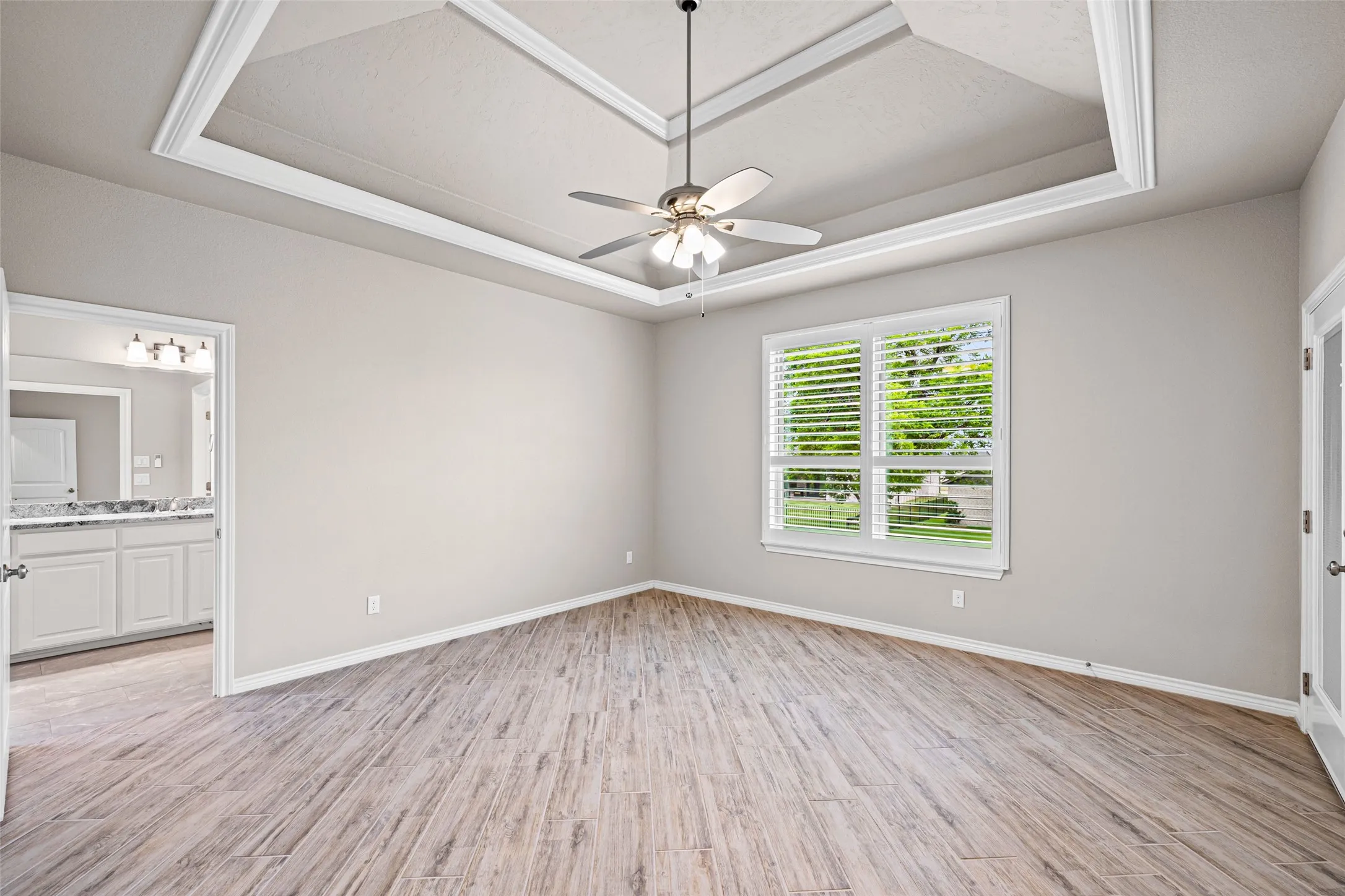 Spacious room featuring wood-finish flooring and a tray ceiling with crown molding
