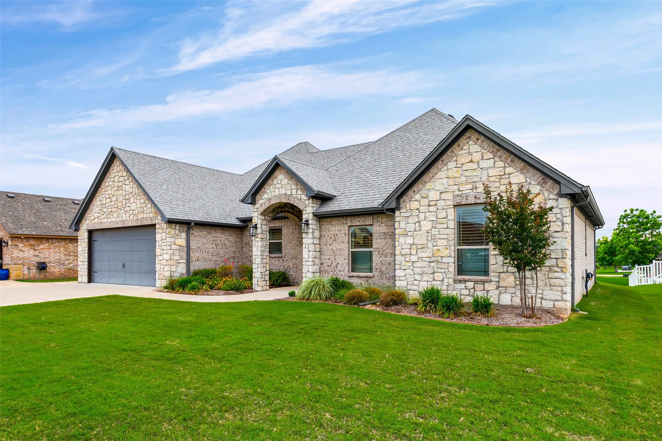 Stone and brick exterior with a gray shingle roof