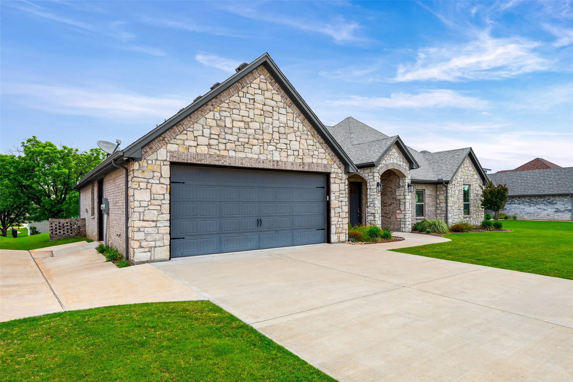 Stone and brick exterior with a prominent two-car garage featuring a dark gray door
