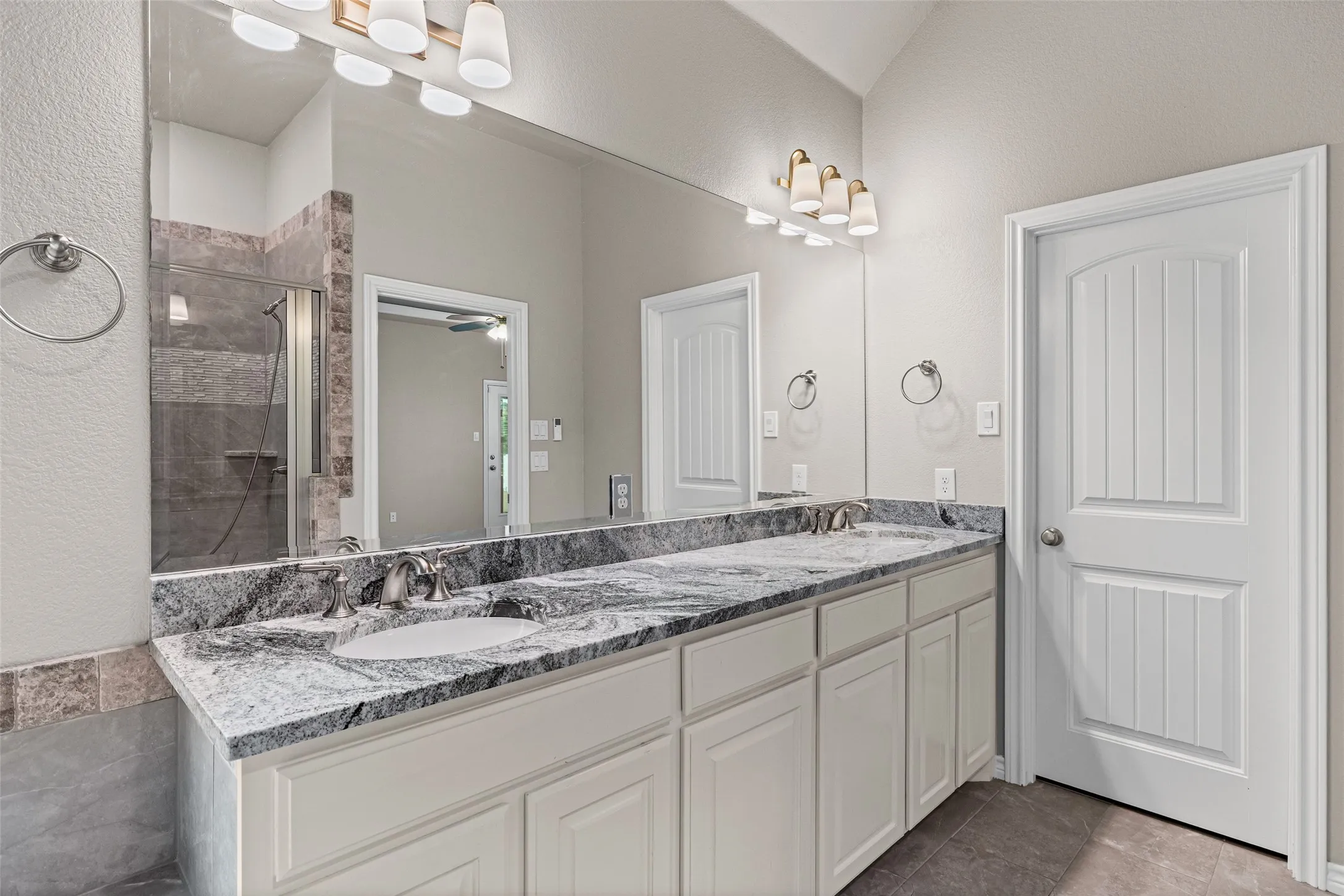 Double vanity featuring a gray-patterned countertop, dual undermount sinks, and brushed nickel faucets