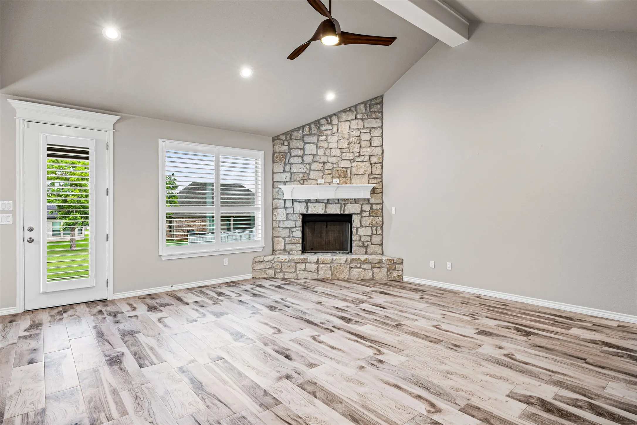 Spacious living area featuring a vaulted ceiling, recessed lighting, and wood-finish flooring