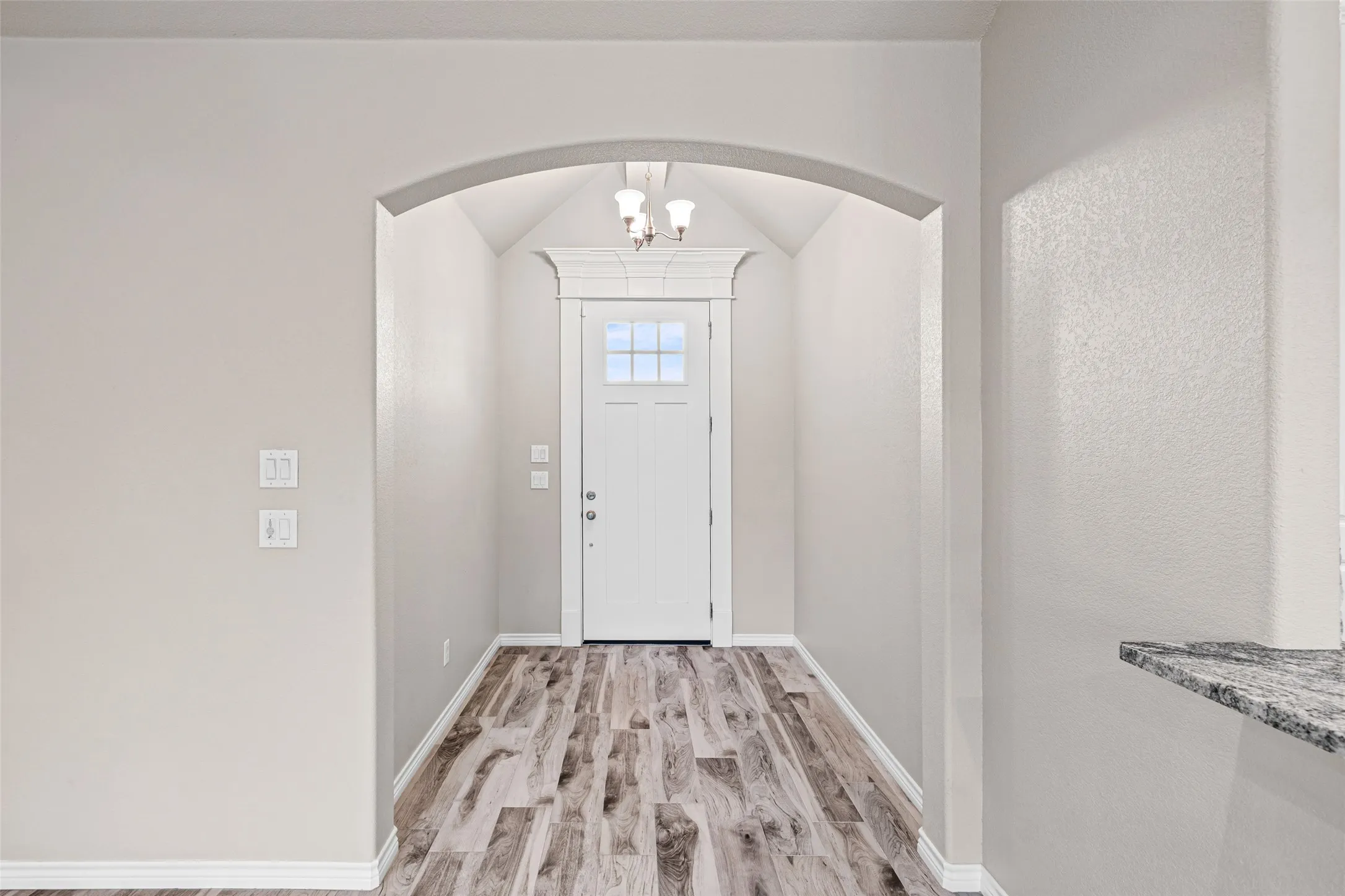 Inviting entry foyer featuring a vaulted ceiling and an arched doorway