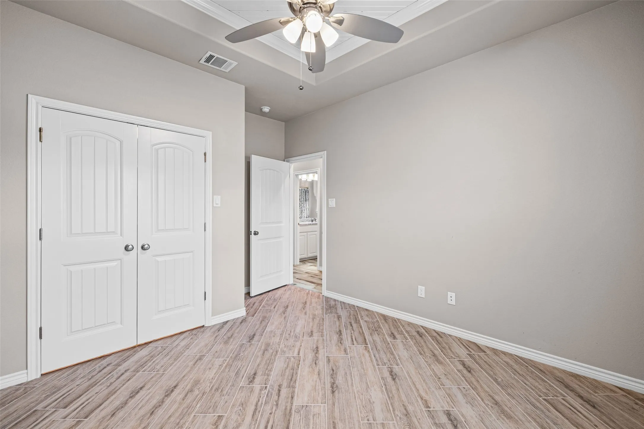 Spacious room featuring wood-look tile flooring, light neutral wall paint, and white baseboards