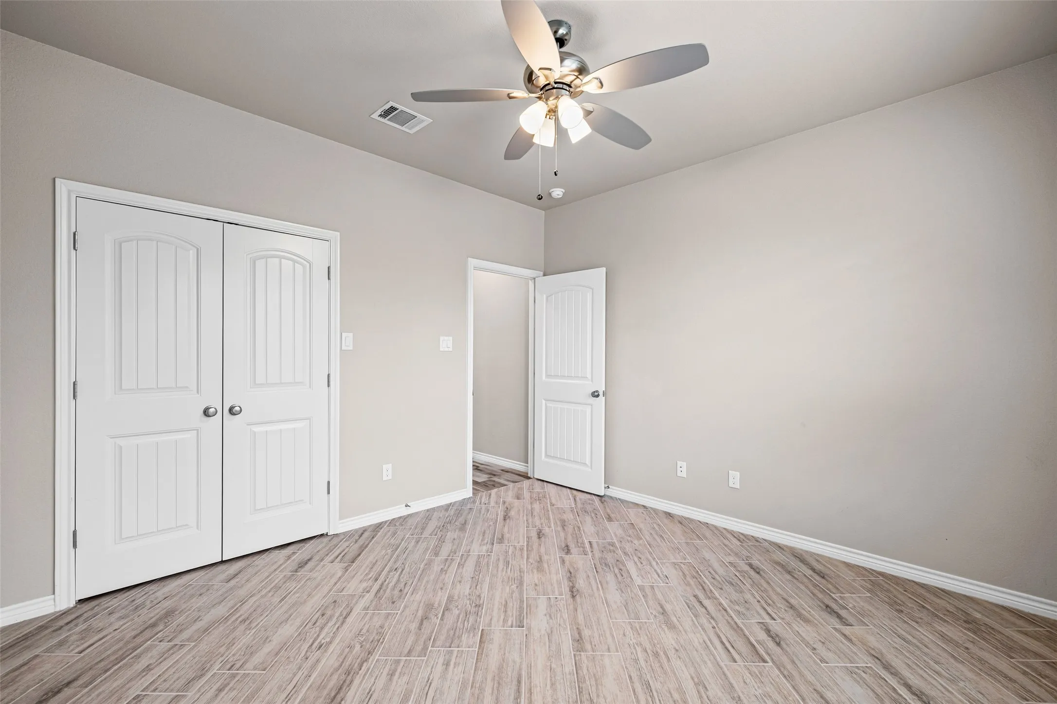 Room featuring wood-finish flooring, light neutral wall paint, and white trim