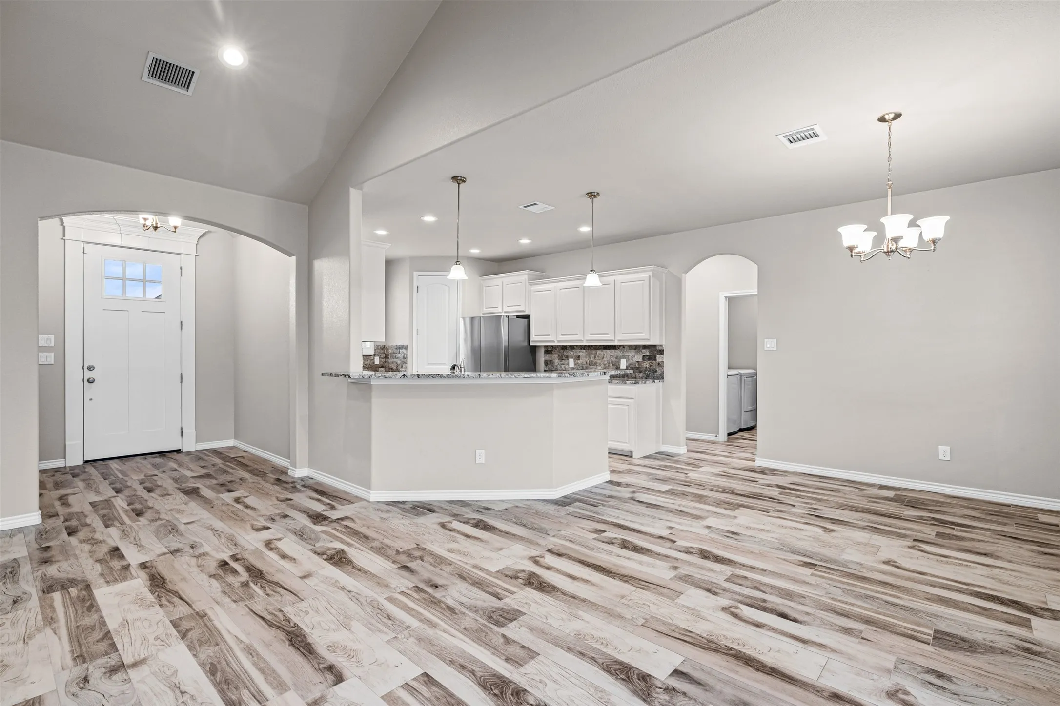 Open-concept living area featuring wood-finish flooring, vaulted ceiling, and recessed lighting