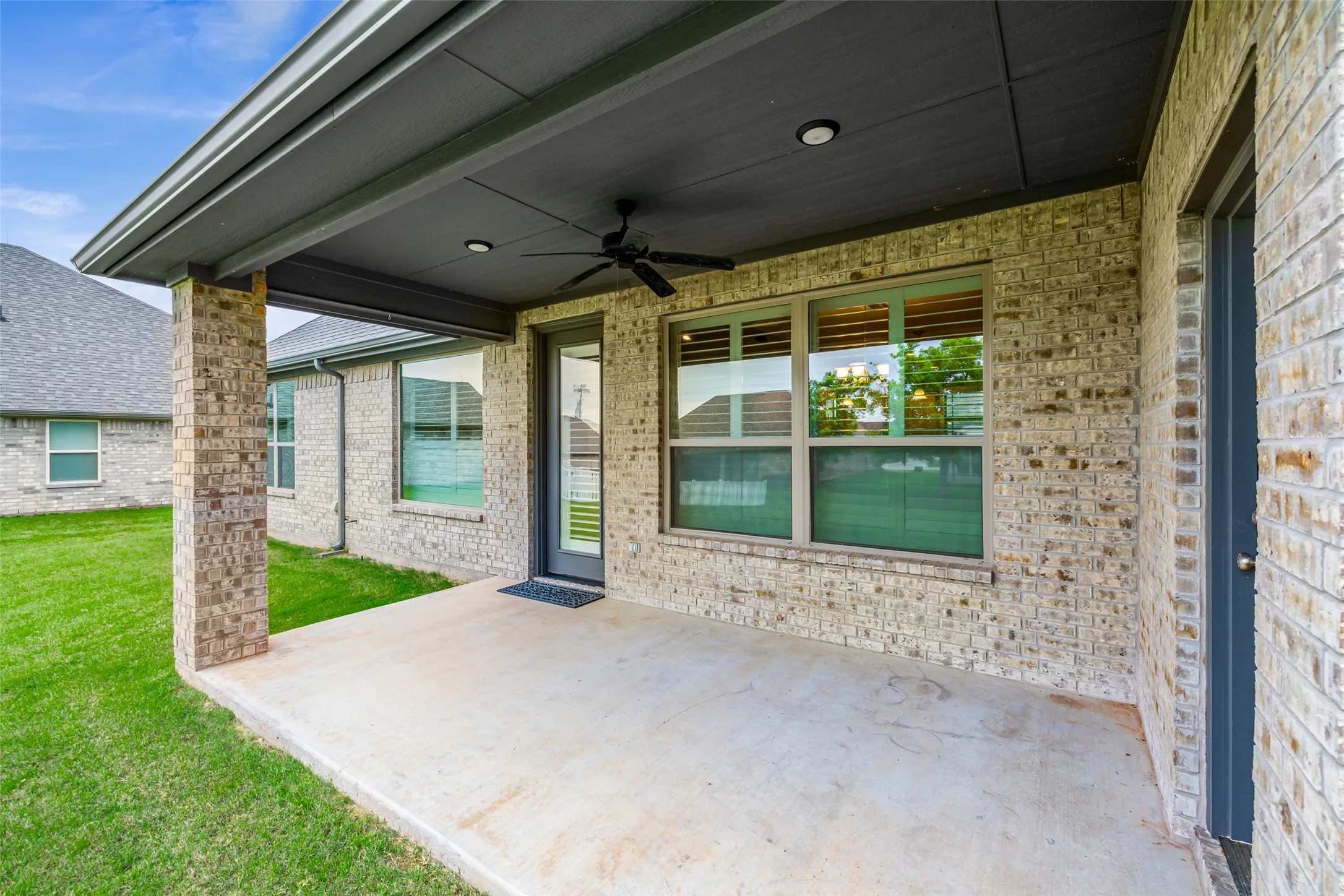Covered patio featuring a concrete slab, brick support columns, and a dark ceiling with recessed lighting