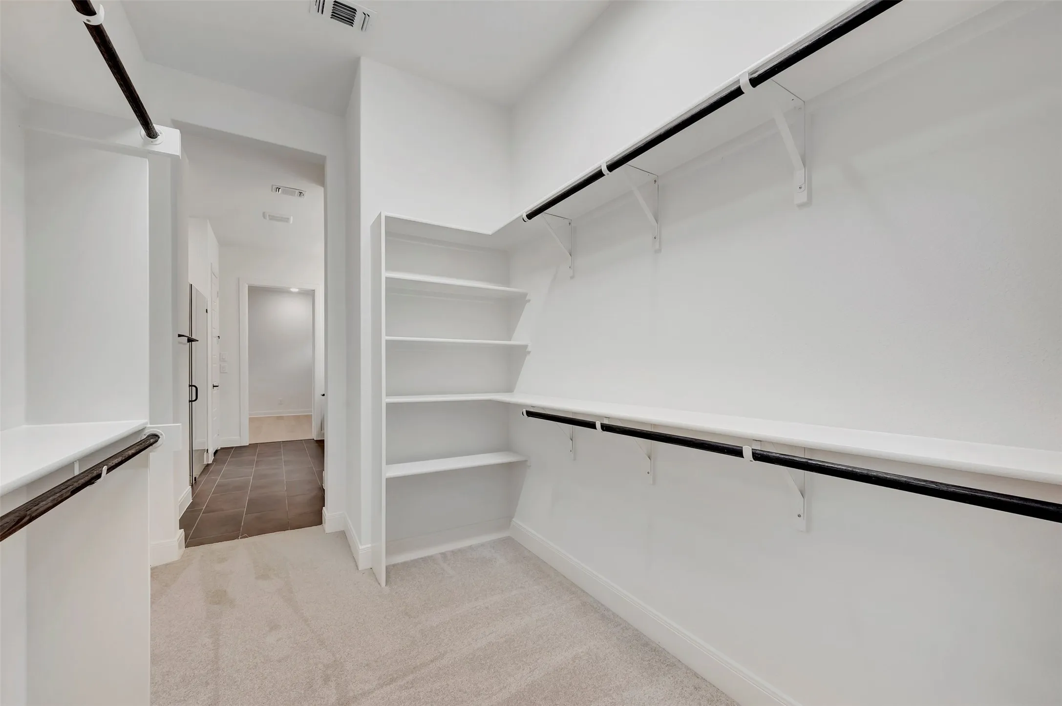 Built-in shelving, hanging rods, carpet flooring, and white painted walls