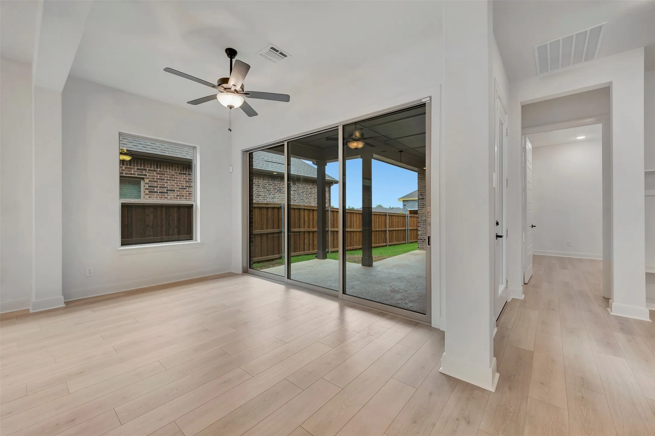 Light wood-finish flooring, ceiling fan, and sliding glass door