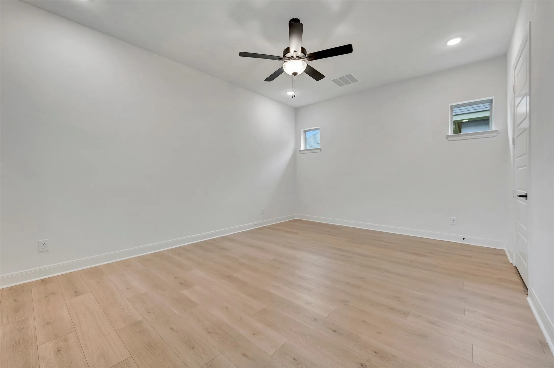 Wood-finish flooring, recessed lighting, ceiling fan, and two transom windows