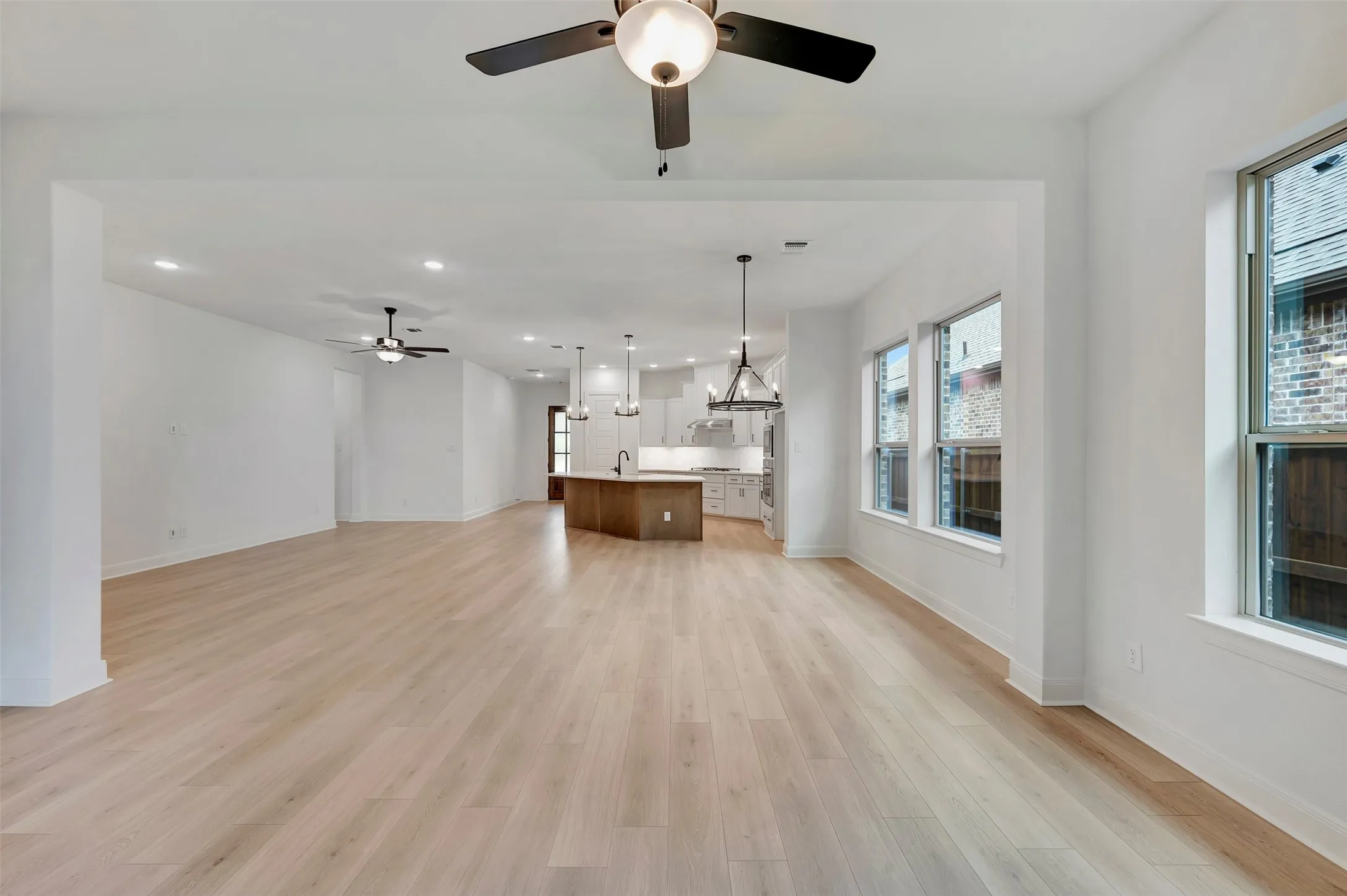 Expansive open-concept space featuring light wood-finish flooring, recessed lighting, and multiple windows