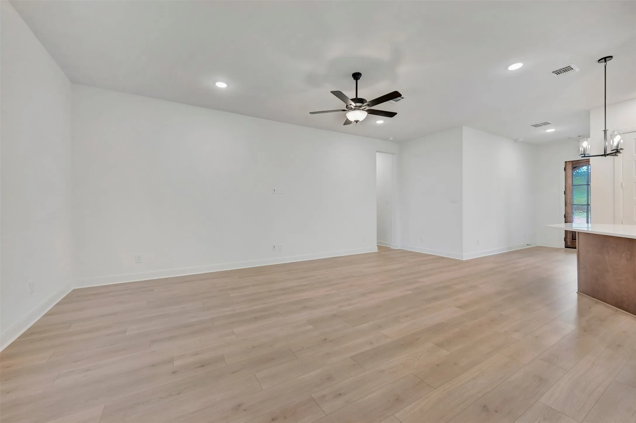 Recessed lighting, wood-finish flooring, ceiling fan, and a kitchen island with pendant lighting