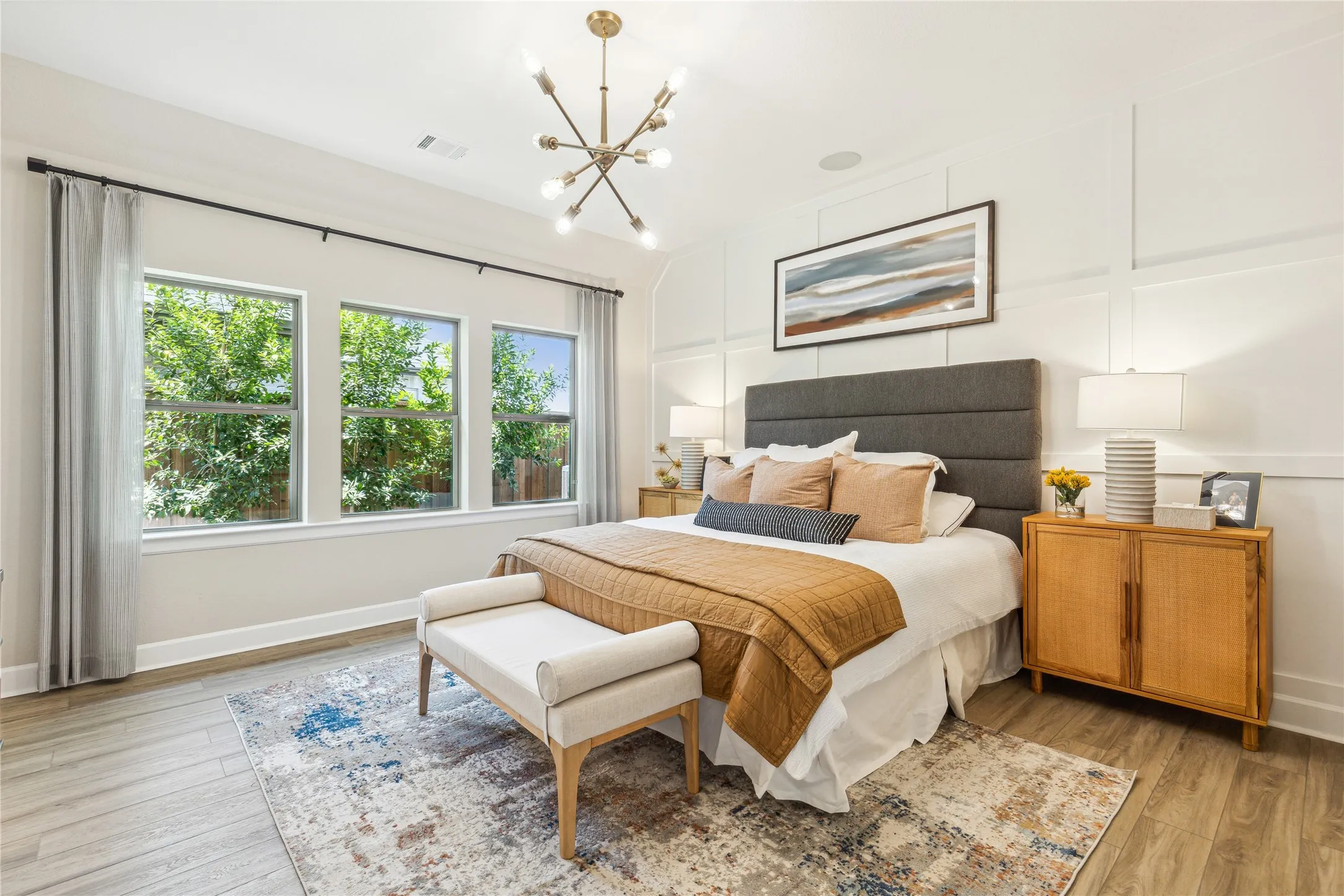 Spacious room featuring three large windows, wood-finish flooring, and a modern chandelier