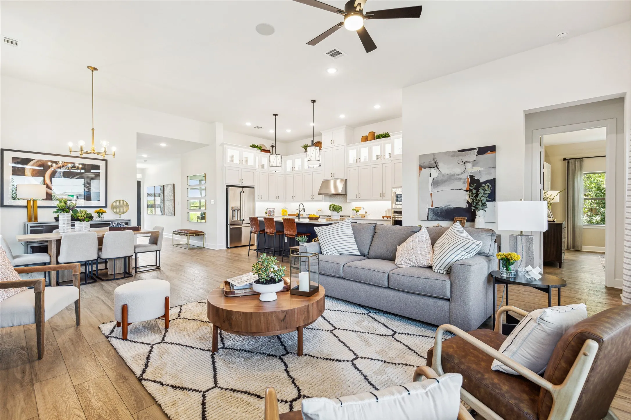 Open-concept living space featuring a blue upholstered sofa, wood-finish flooring throughout, and a round wood-top coffee table anchoring the room