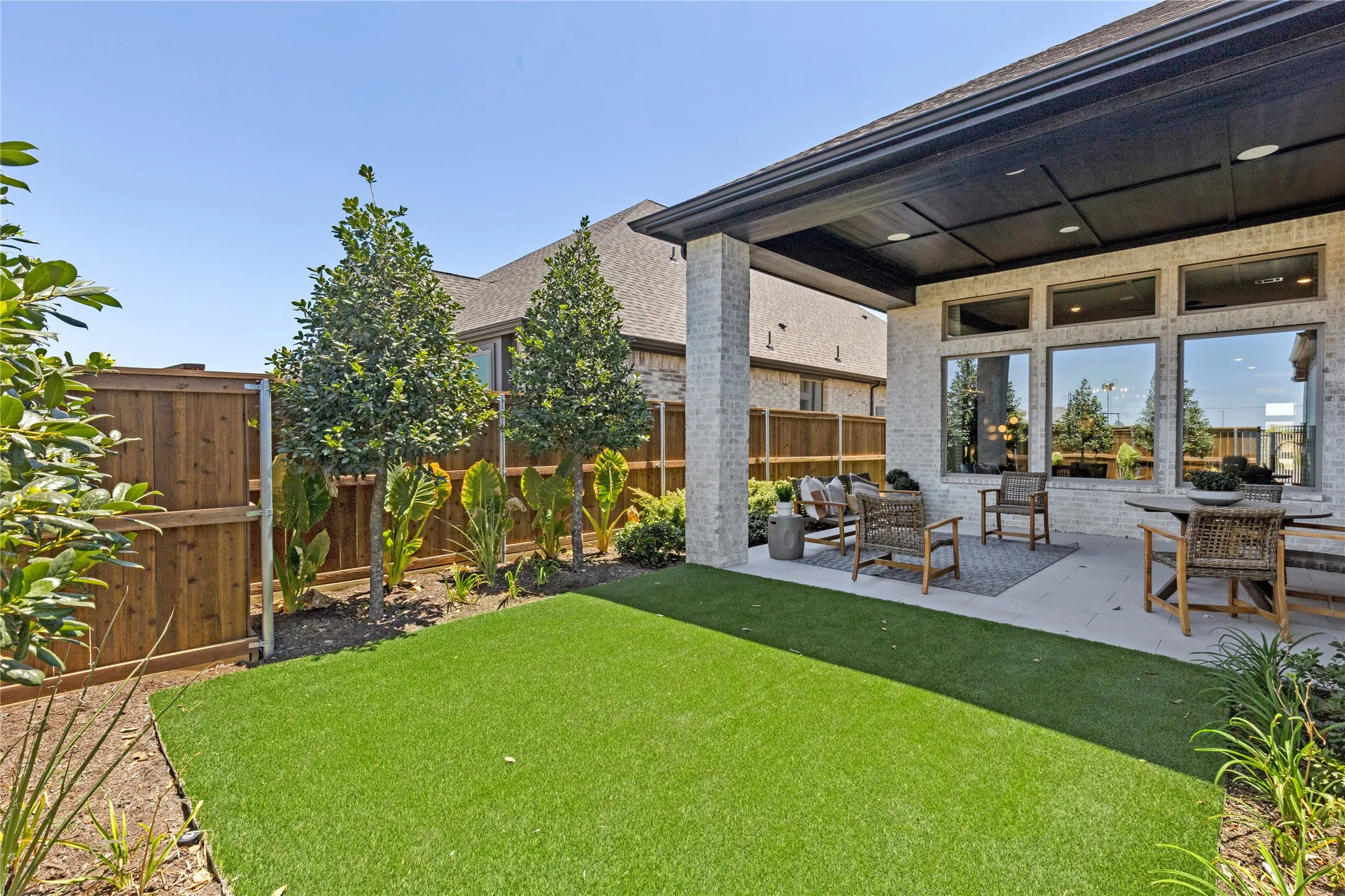 Expansive backyard oasis featuring a manicured lawn, mature landscape plantings, and wooden privacy fencing